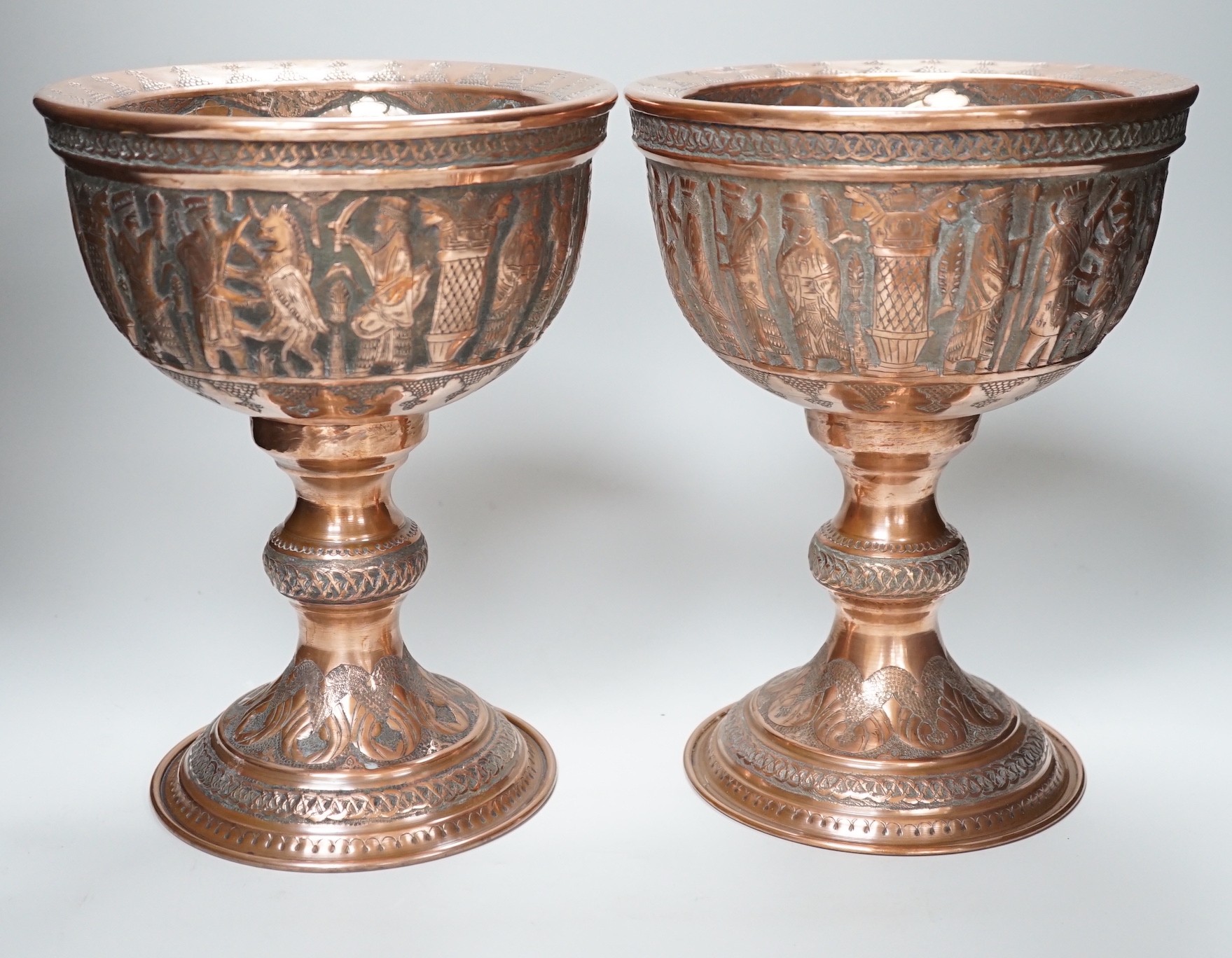 A pair of Persian copper figural decorated chalices, 27cms high                                                                                                                                                             
