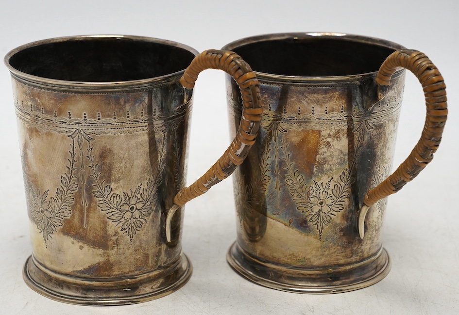 A pair of George V engraved silver mugs, with rattan handles, William Aitken, Birmingham, 1920, height 95mm, gross weight 5.9oz. Condition - fair                                                                           