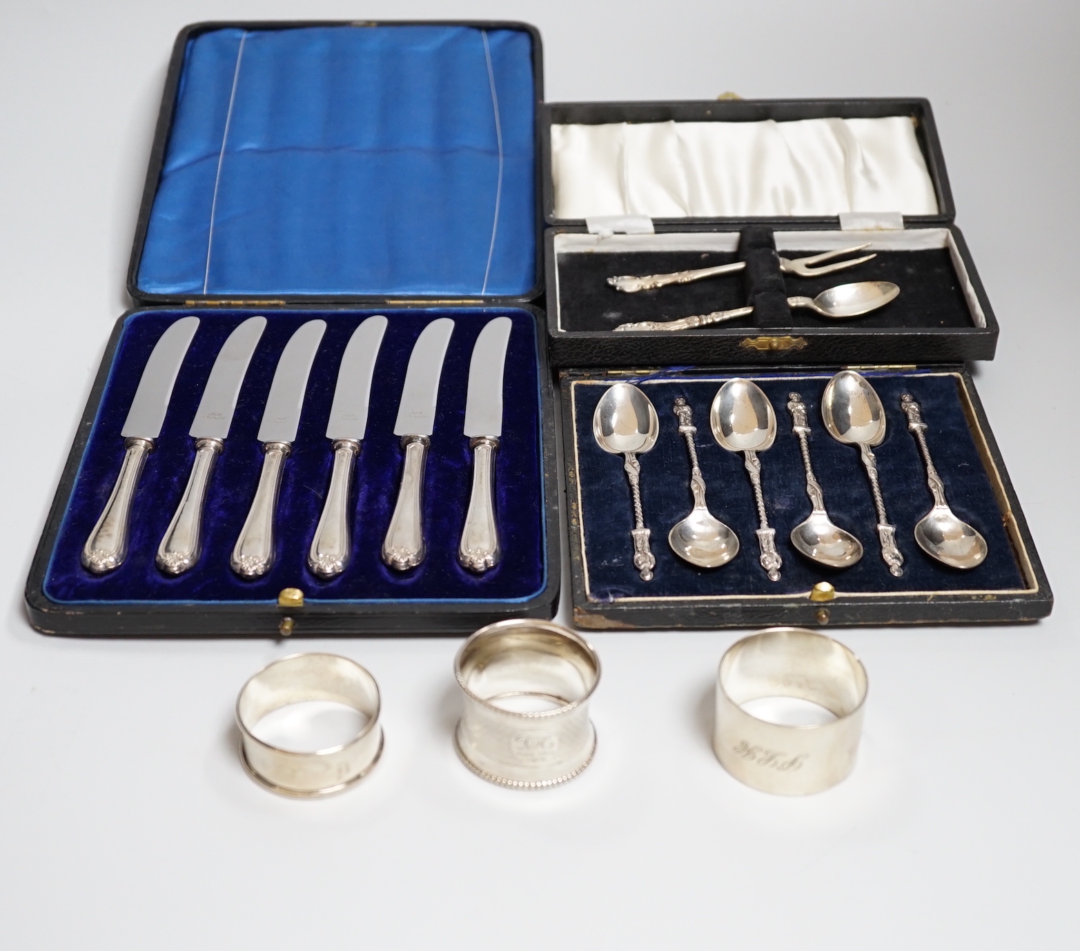 A cased of six George V silver apostle teaspoons, Sheffield 1917, 92 grams, a cased two piece christening fork and spoon (made up), 27 grams, a cased set of six silver handled tea knives and three silver napkin rings, 63