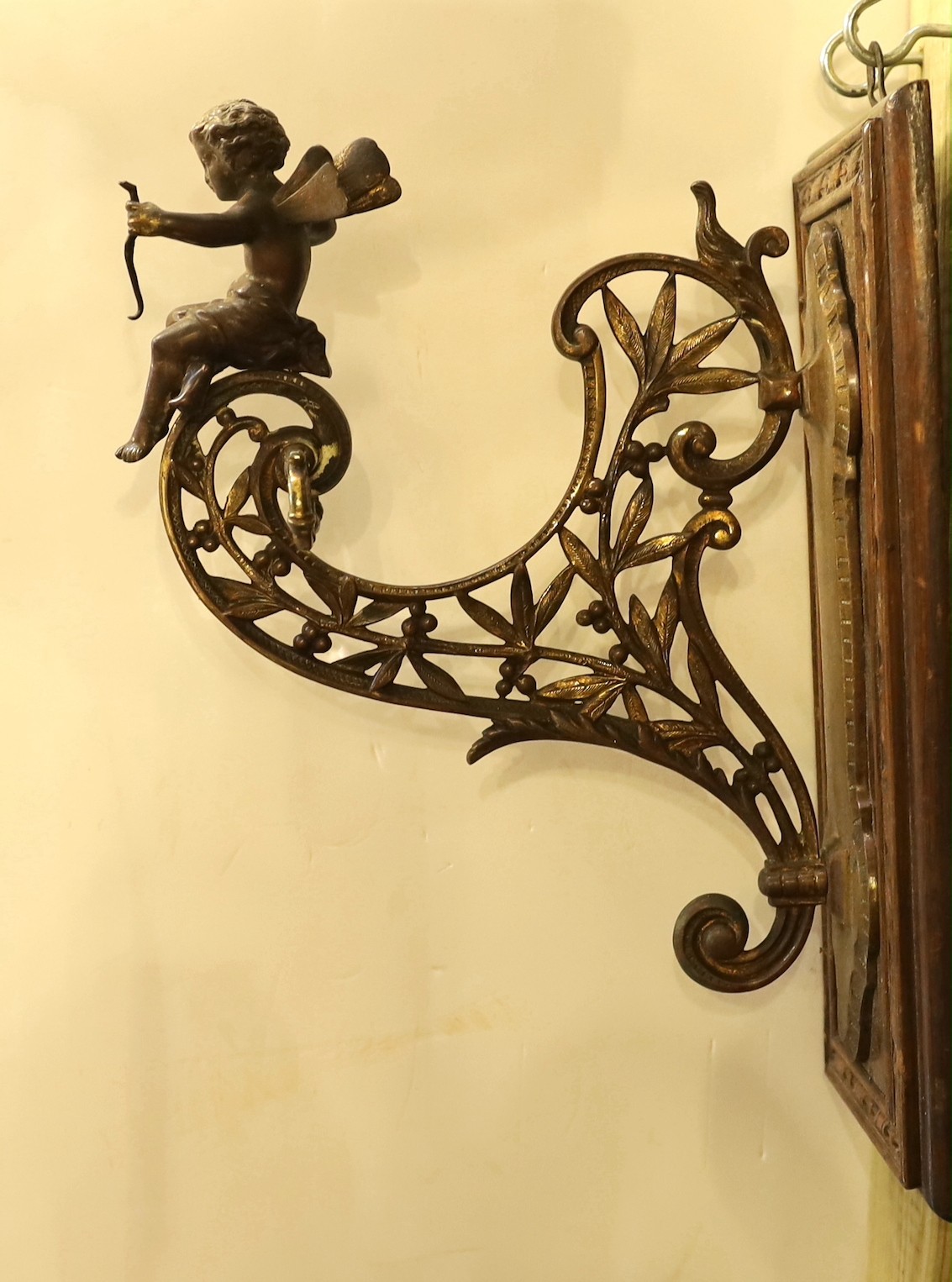A late Victorian aesthetic movement ormolu wall bracket, modelled with Cupid and laurel leaves, mounted on an oak wallplate, height 34cm. depth 25cm                                                                        