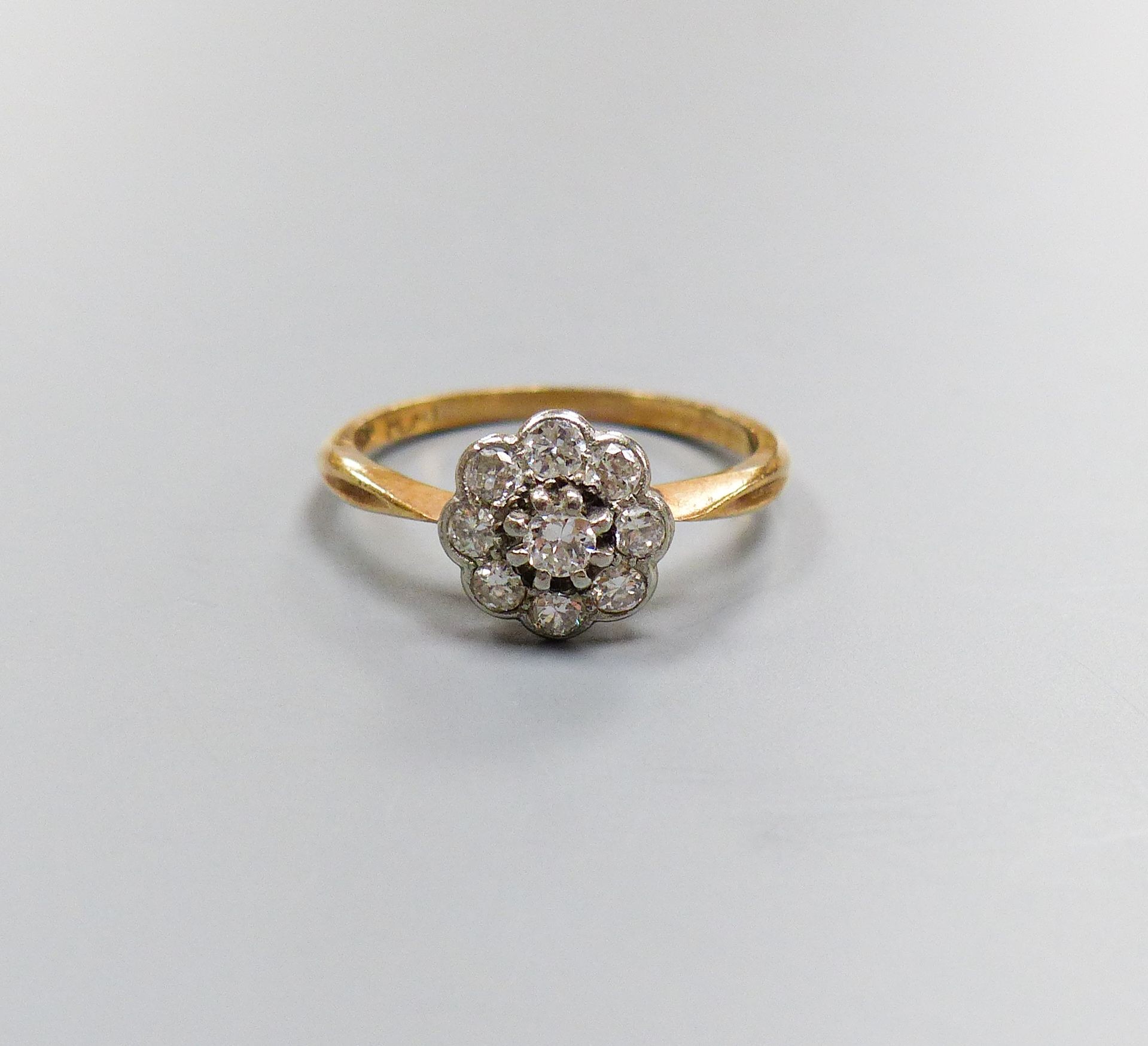 An 18ct & plat, circular diamond cluster set ring, size M/N, gross weight 2.5 grams.                                                                                                                                        