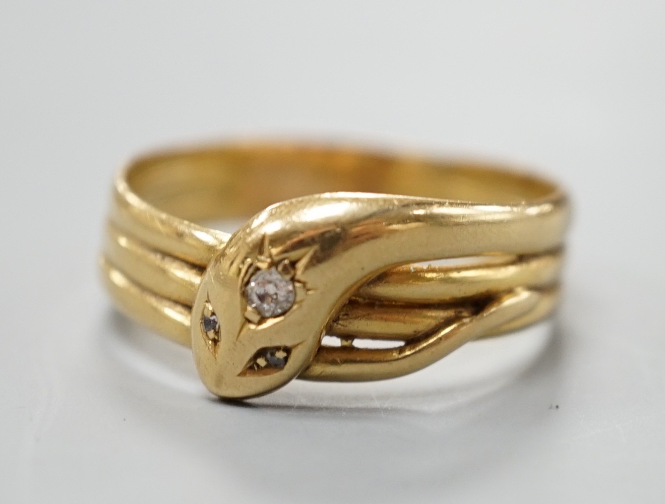 An Edwardian 18ct gold and diamond chip set serpent ring, size X/Y, gross 5.6 grams.                                                                                                                                        