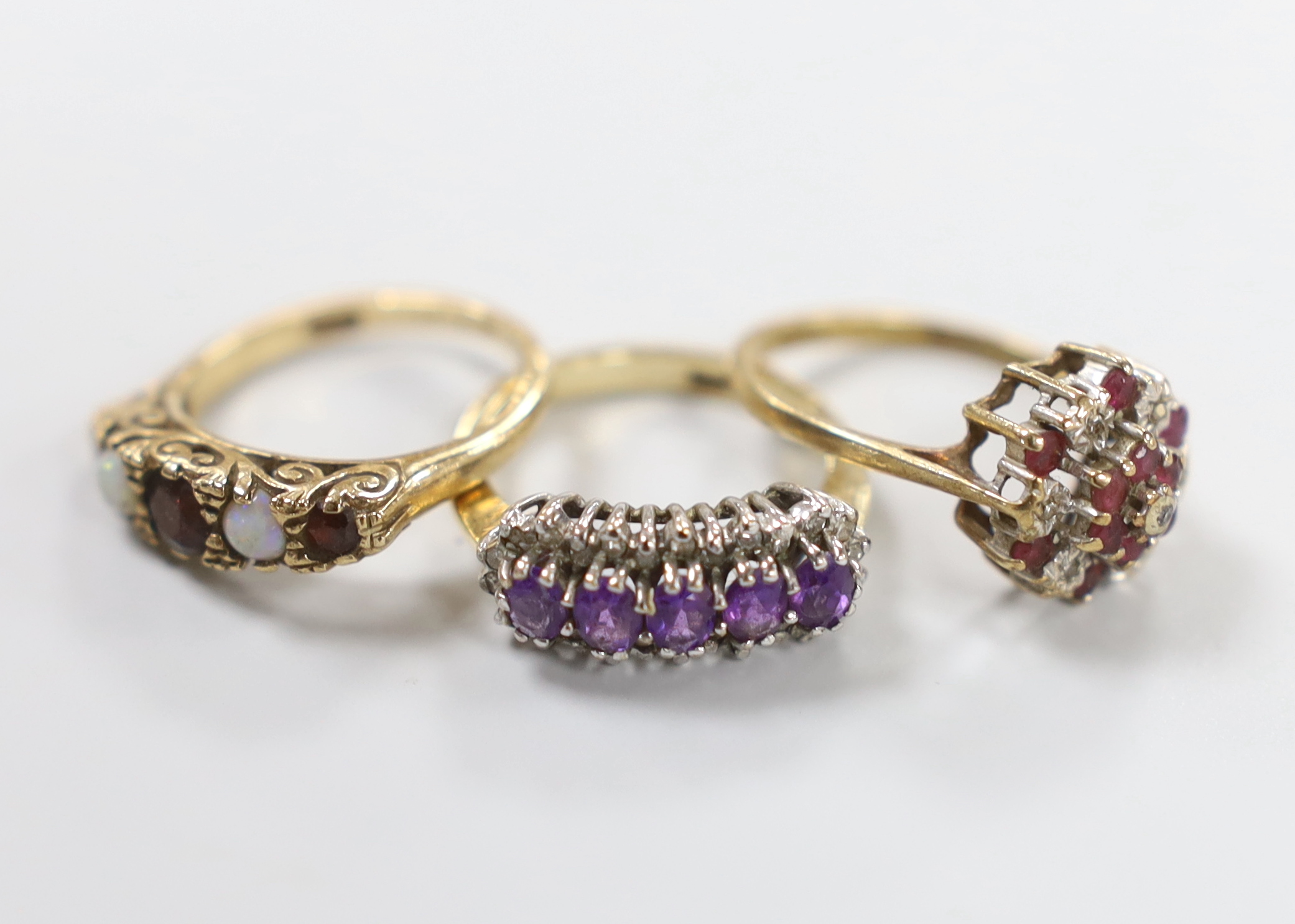 Three 9ct gold dress rings: white opal and ruby, size L, diamond and amethyst, size L and ruby and diamond, size M                                                                                                          