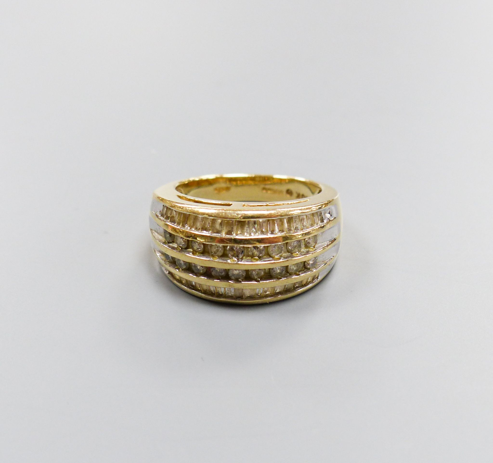 A modern 9ct gold and four row round and baguette cut diamond set dress ring, size N/O, gross 7.2 grams.                                                                                                                    