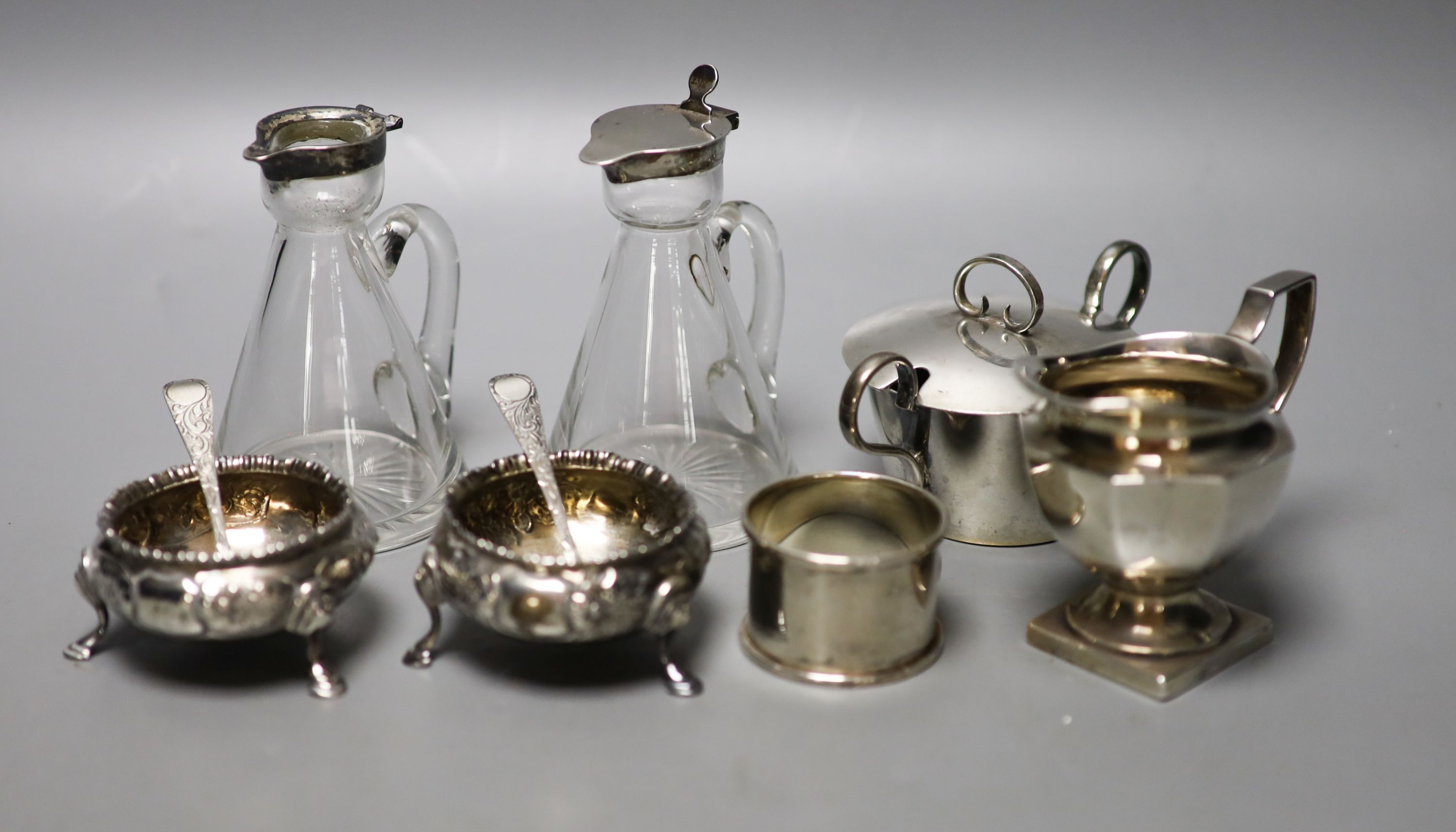 A pair of Victorian silver bun salts, London, 1859, two silver spoons, two mounted whisky tot jug (one a.f.), a silver cream jug, a silver napkin ring and a silver two handled pot and cover.                              