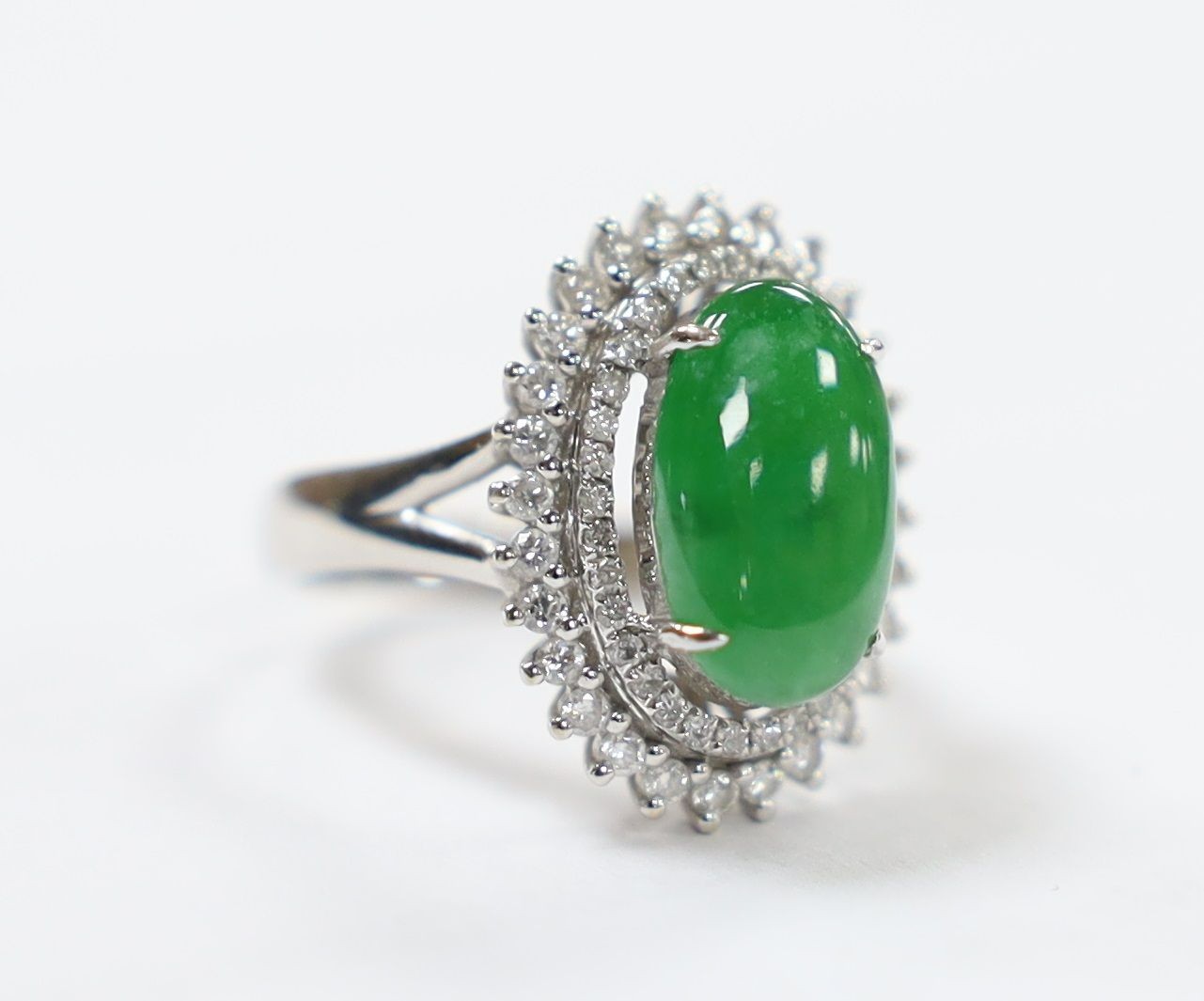 A modern 18k white metal, cabochon jade and two row diamond chip set oval cluster ring size L, gross weight 6.4 grams.                                                                                                      