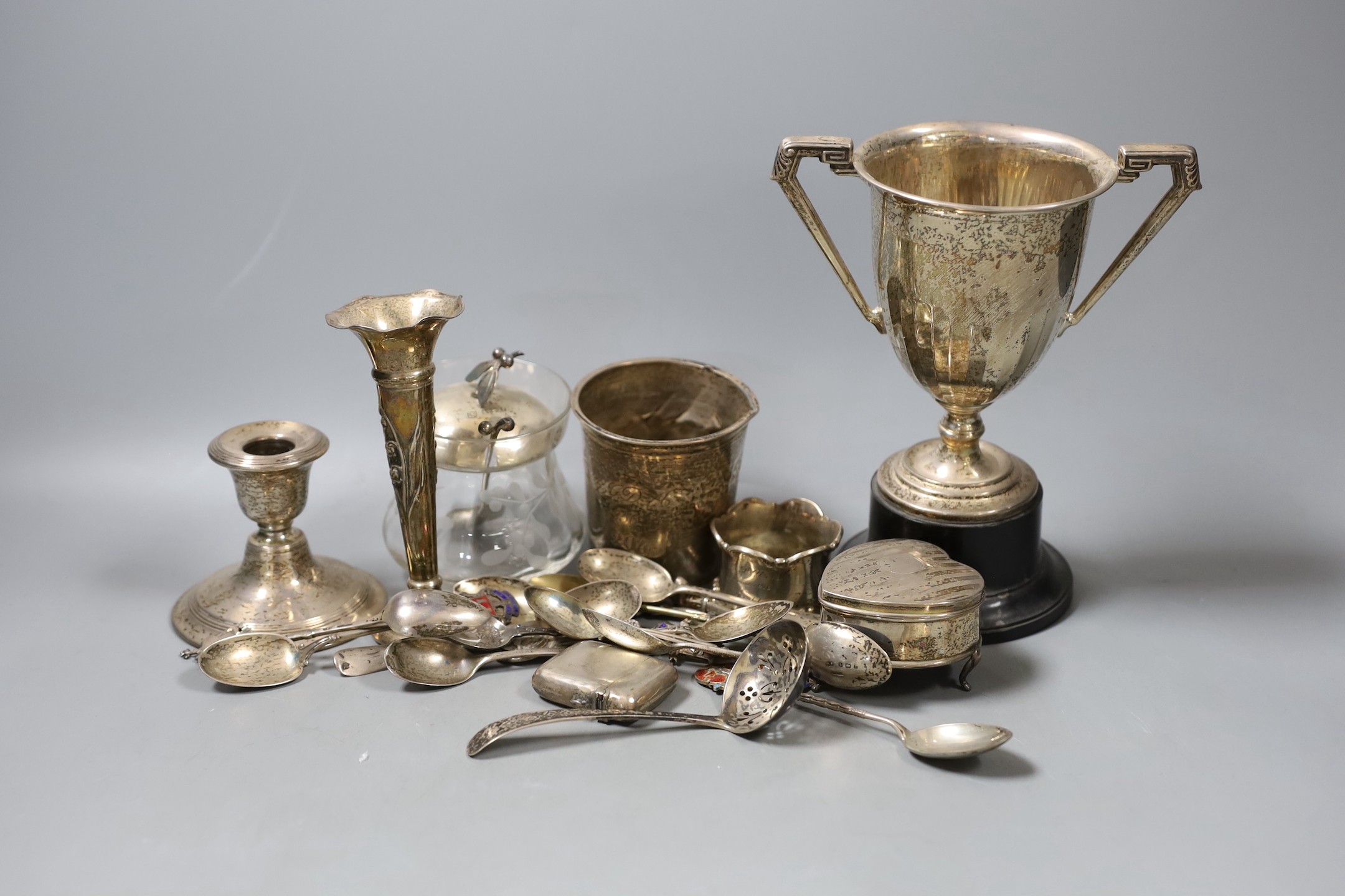 A collection of eighteen small pieces of silver and white metal items, including a silver topped glass preserve jar, trophy cup, flatware, napkin ring, trinket box, etc.                                                   