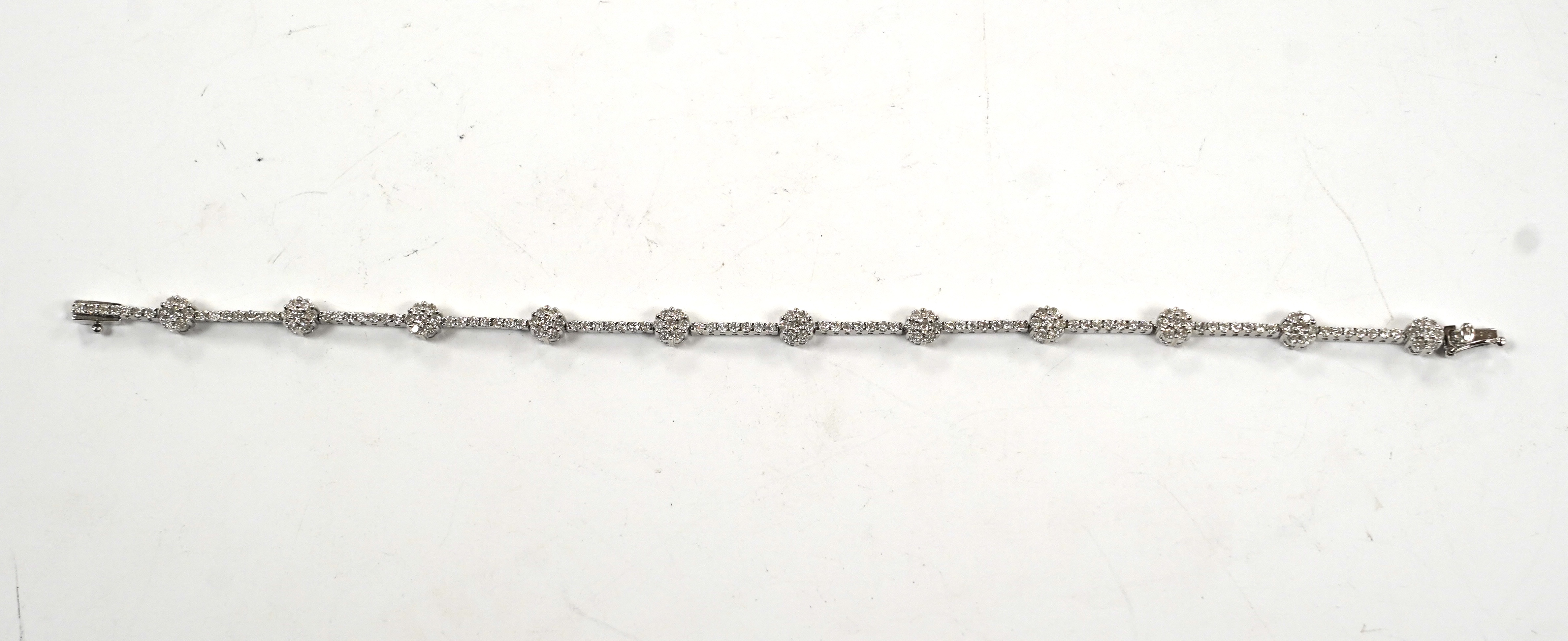 A modern 18k white metal and diamond cluster set line bracelet, 17.8cm, gross weight 8.8 grams.                                                                                                                             