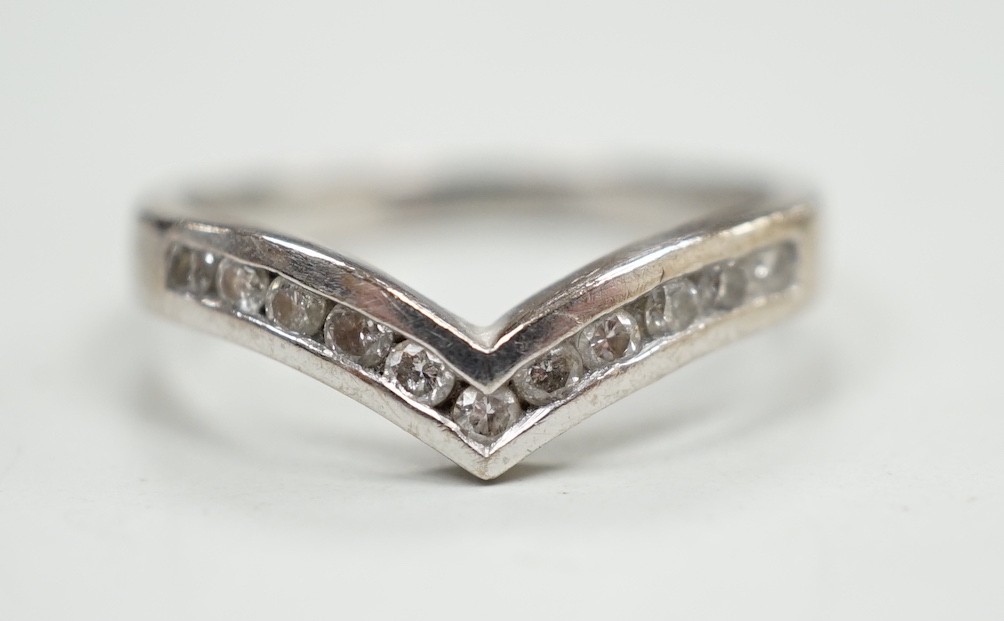 A modern 18ct white gold and channel set diamond chip wishbone shaped ring, size M, gross 3.4 grams.                                                                                                                        