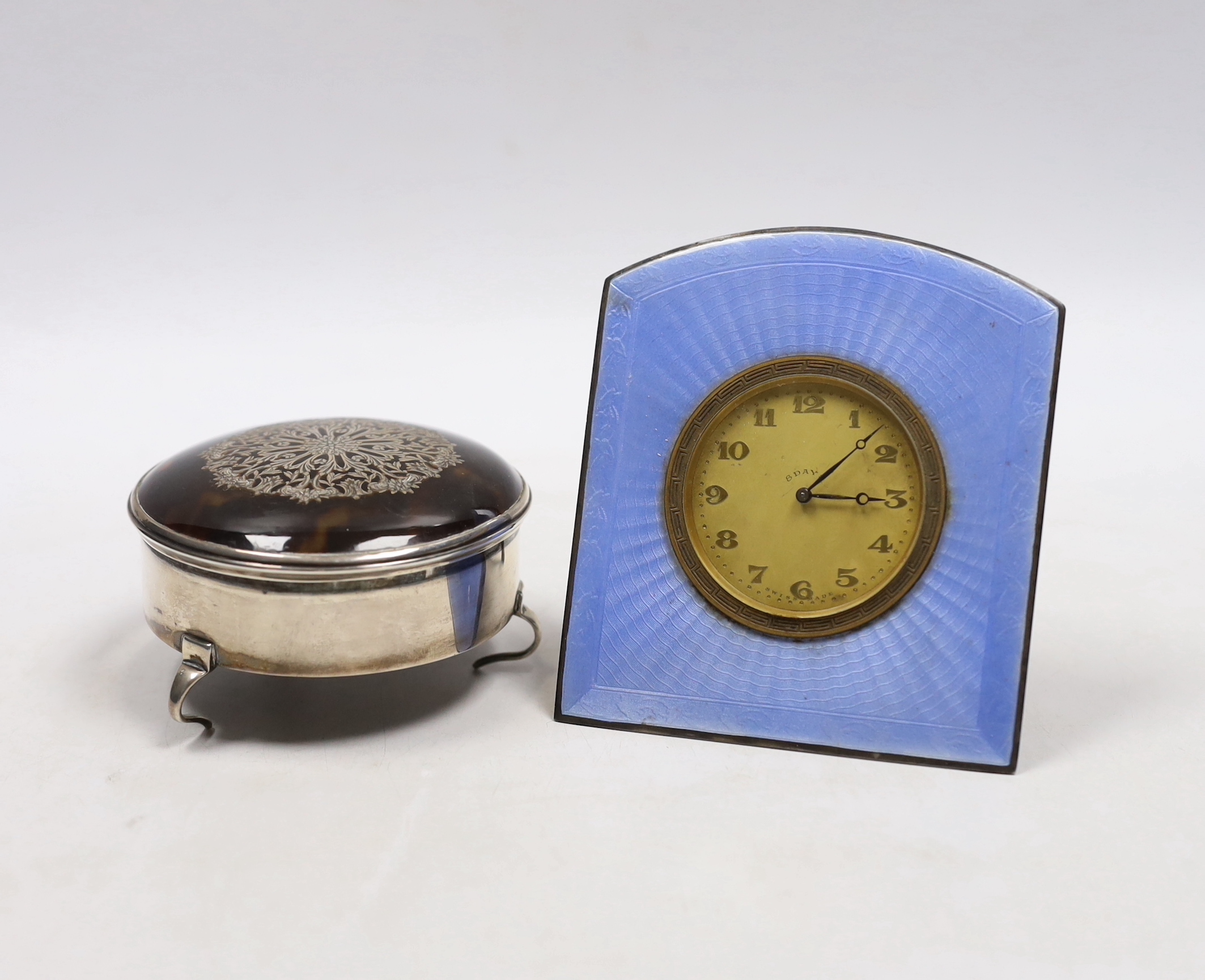 A George V silver and tortoiseshell pique mounted trinket box, by William Comyns, London, 1913, 79mm and an enamelled bedside timepiece.                                                                                    