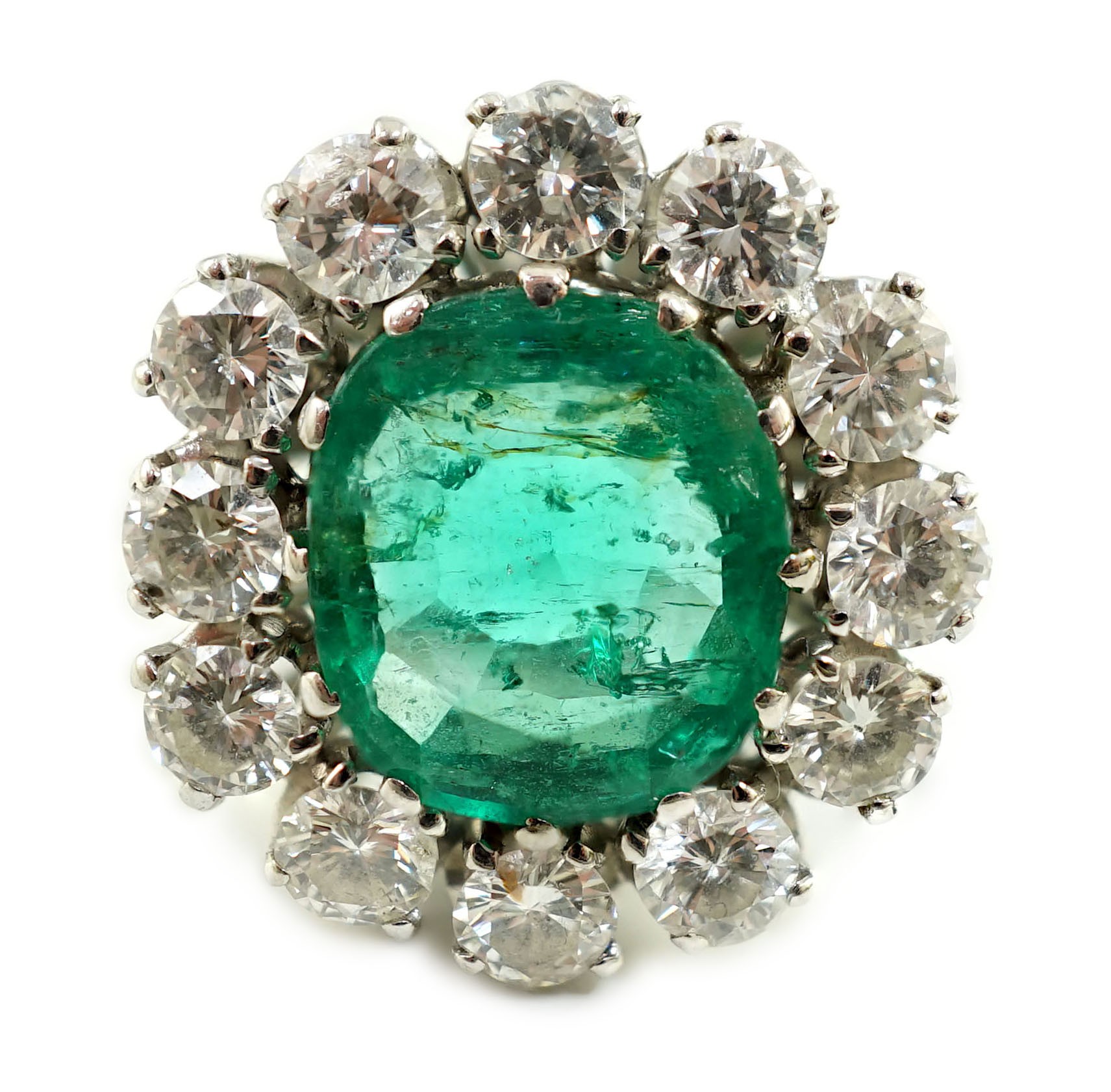 An impressive platinum, emerald and diamond set oval cluster dress ring                                                                                                                                                     
