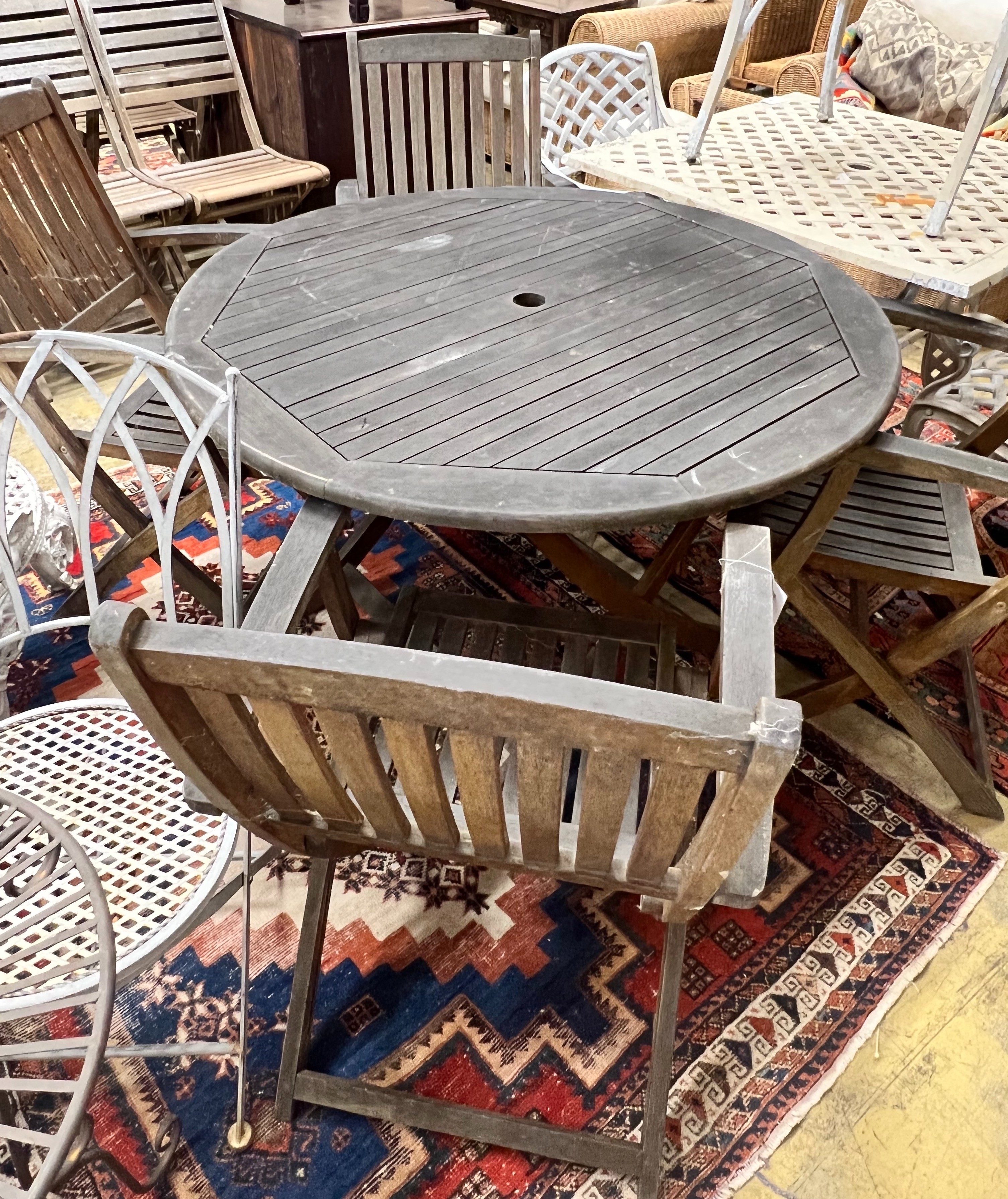 A circular weathered teak folding wooden garden table, diameter 110cm height 72cm, together with four elbow chairs                                                                                                          