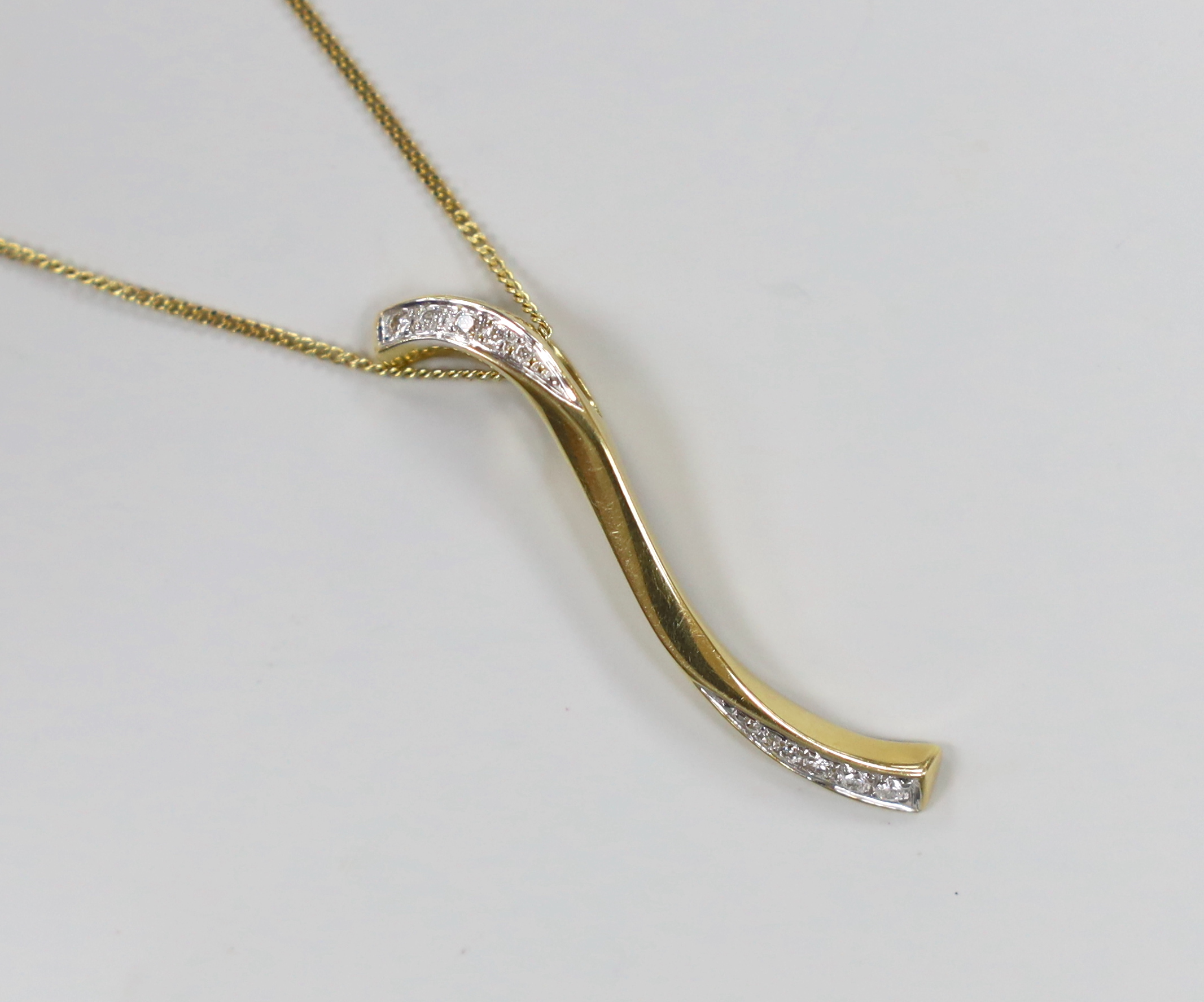 A modern 18ct gold and diamond chip 'S' shaped pendant, 38mm, on an 18ct gold chain, 39cm, gross weight 5.3 grams.                                                                                                          