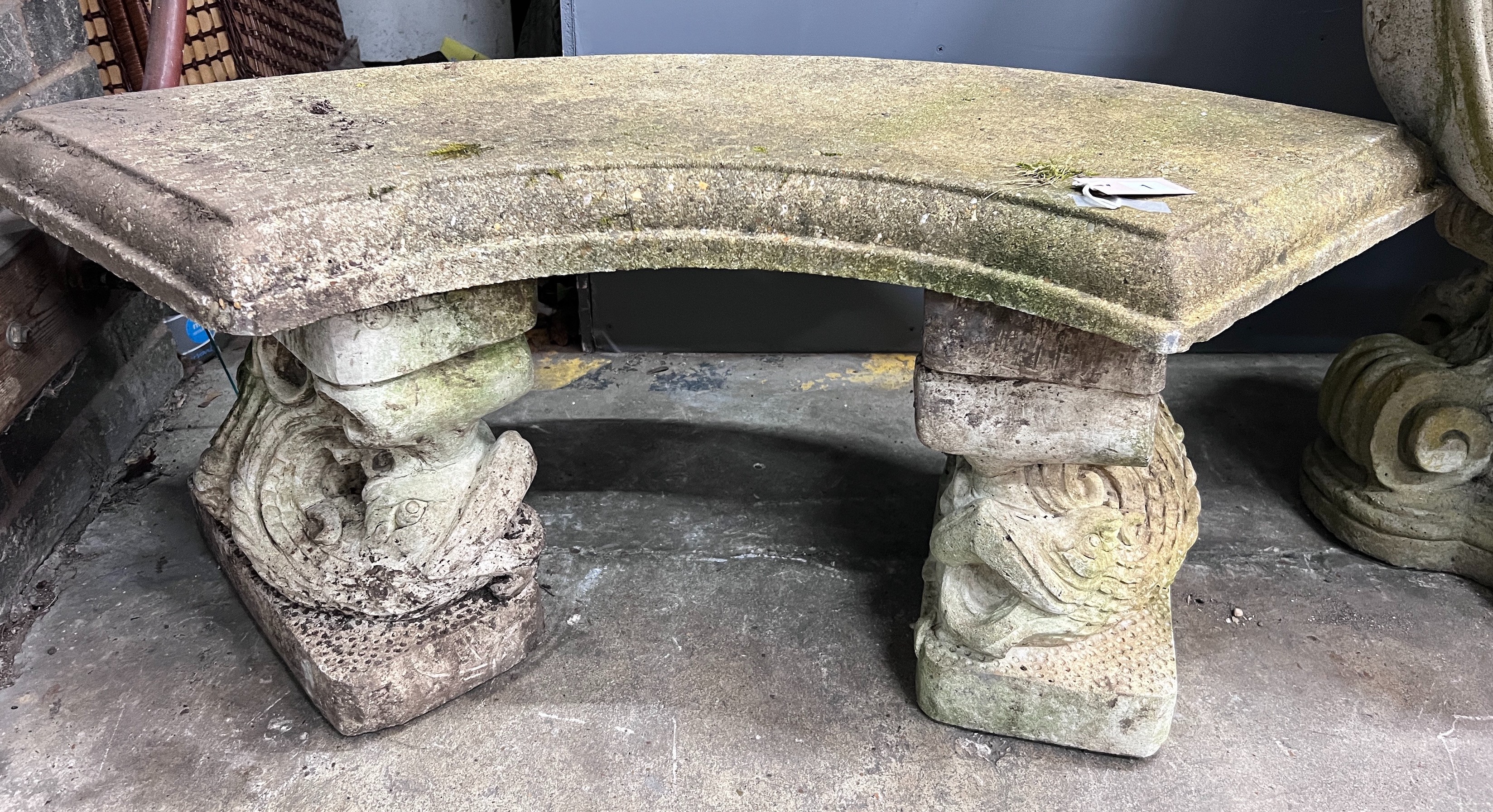 A reconstituted stone curved garden bench with dolphin supports, length 98cm, depth 46cm, height 43cm *Please note the sale commences at 9am.                                                                               