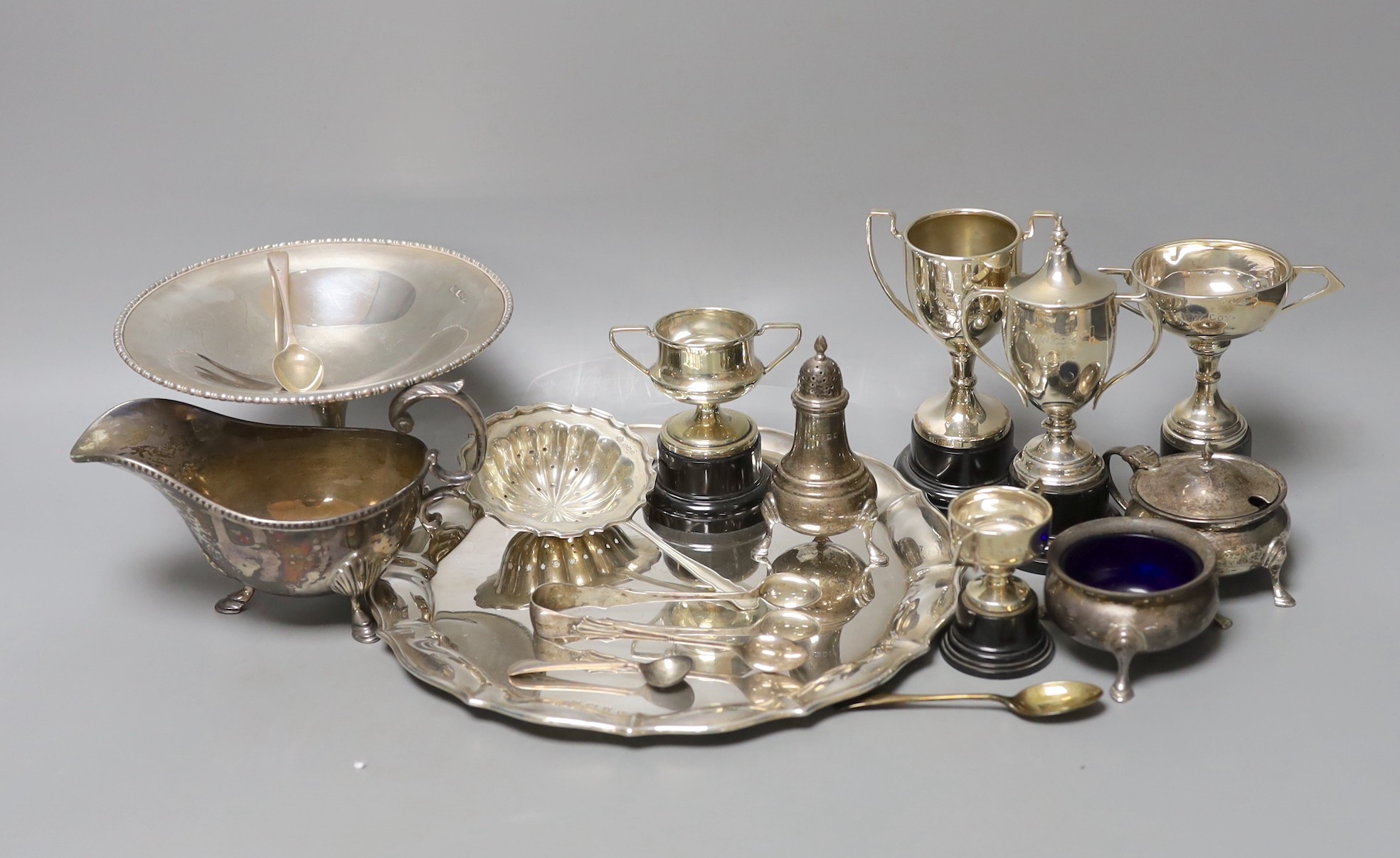 A George V silver salver, a silver tazze, a silver sauceboat, three silver condiments, a silver tea strainer, four items of silver flatware, three small silver trophy cups and two plated cups.                            