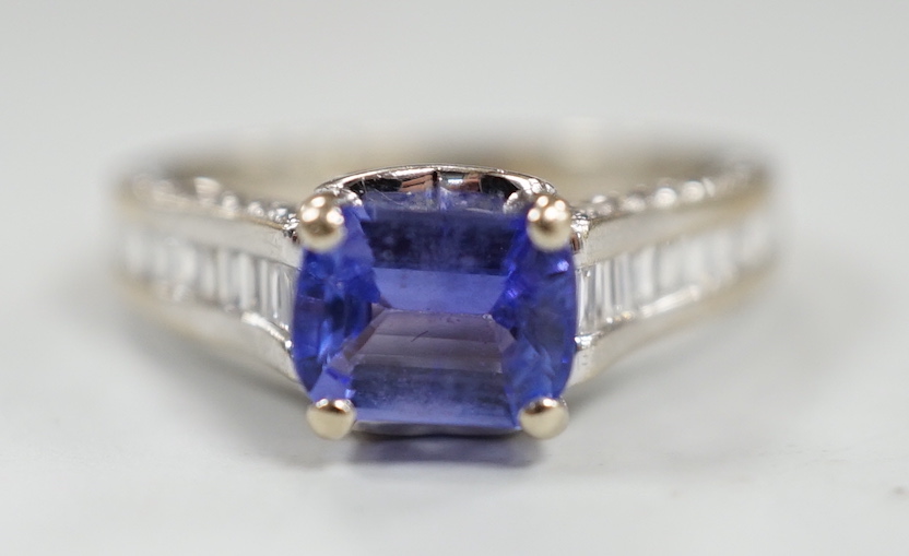 A modern 18ct gold and single stone emerald cut tanzanite set dress ring, with graduated baguette and round cut diamond set shoulders and graduated baguette cut diamond set heart shaped setting, size I, gross weight 4.7 