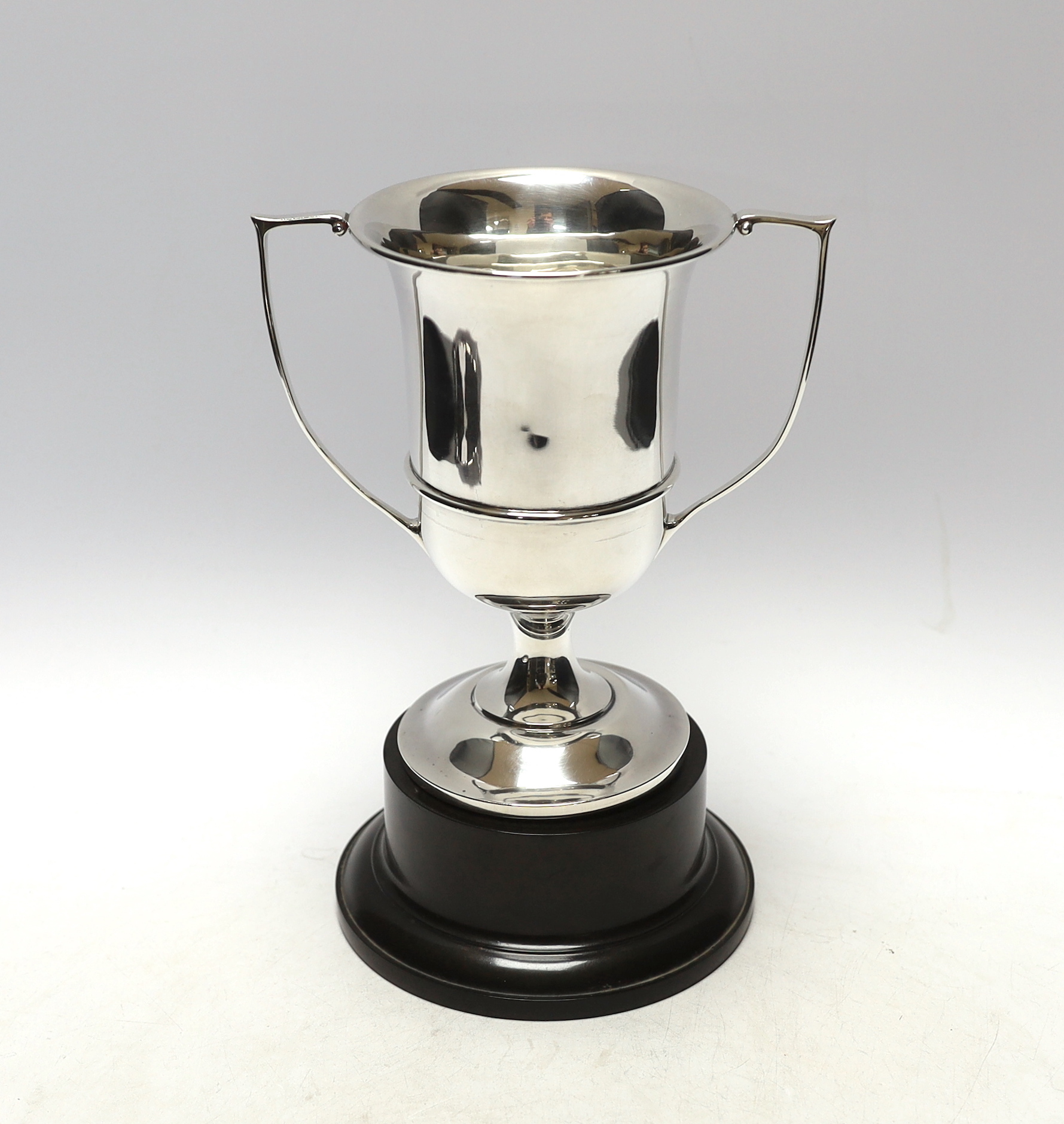 A George V unengraved silver two handled trophy cup, W H Haseler Ltd, Birmingham, 1929, height 17.6cm, 9.5oz, on an ebonised socle.                                                                                         