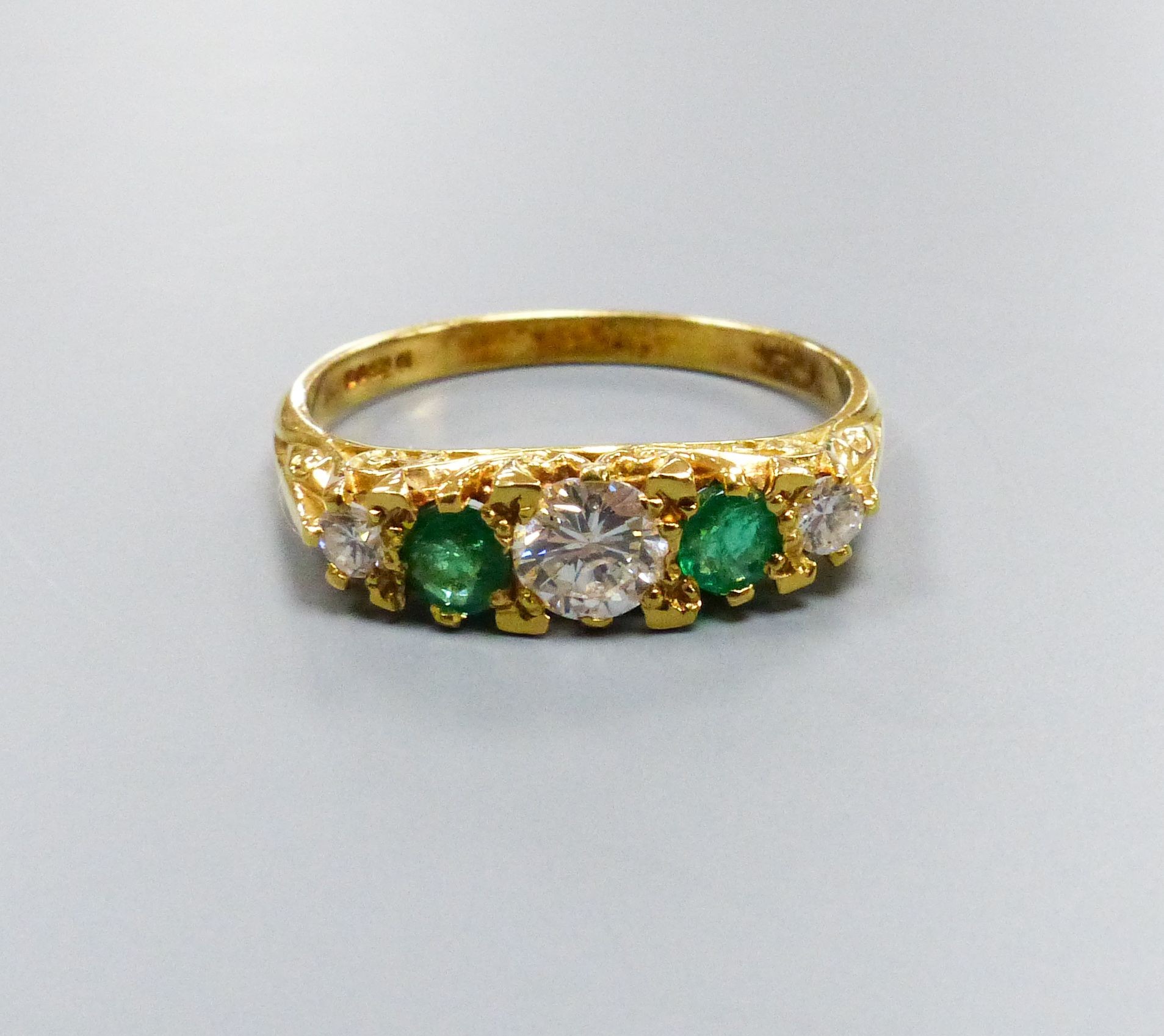 A modern Victorian style 18ct gold, three stone diamond and two stone emerald set half hoop ring, size P, gross weight 3.4 grams.                                                                                           