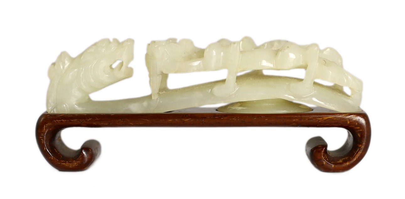 A Chinese white jade ‘dragon’ belt hook, 19th century, 9.4cm long, wood stand                                                                                                                                               