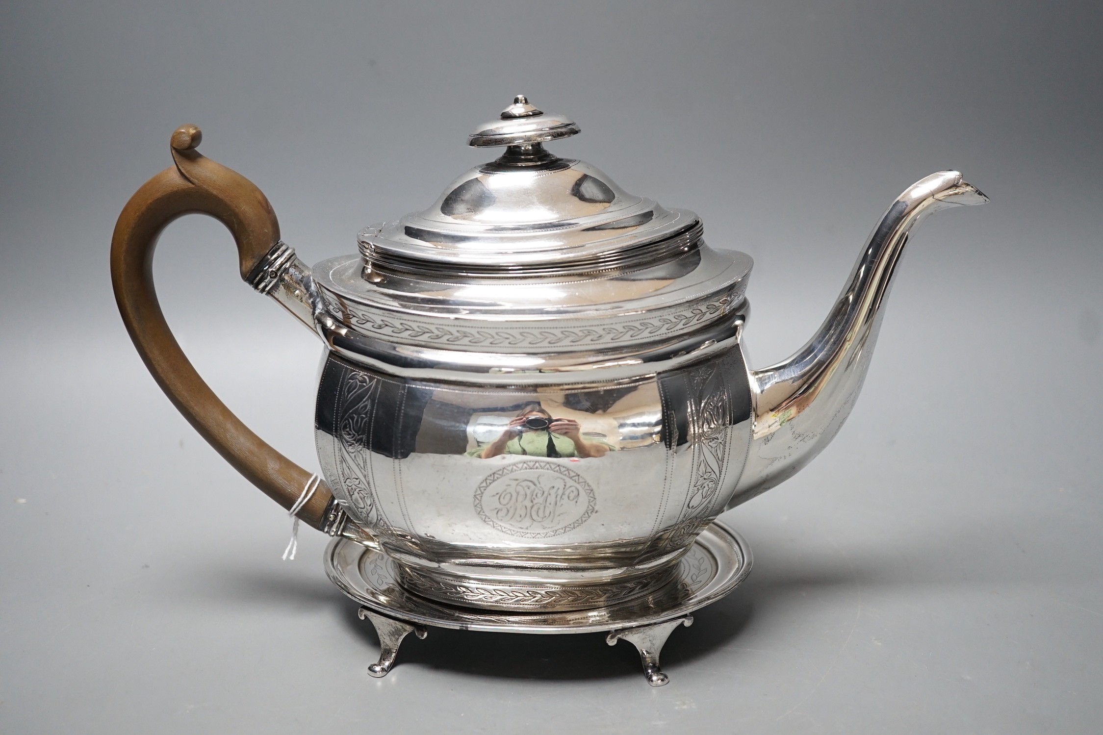 A George III engraved silver oval teapot, Alice & George Burroughs?, London, 1804 and an associated oval silver stand, James Darquits, London, 1805, gross weight 18.3oz.                                                   