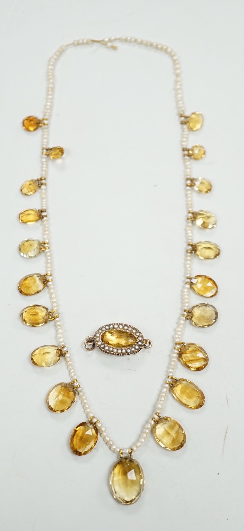 An Edwardian twenty one graduated oval cut citrine set seed pearl necklace (a.f) clasp loose, approx. 34cm.                                                                                                                 