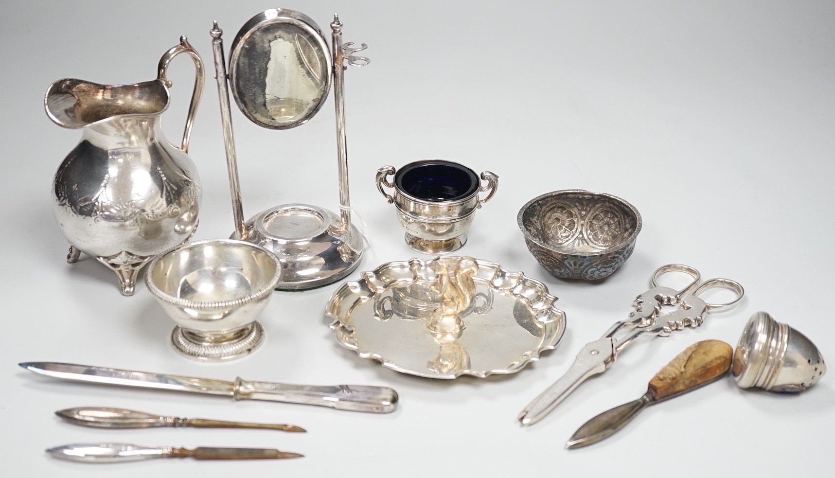 A 1920's silver mounted manicure stand with mirror and three associated implements, a small silver two handled salt, modern silver bowl, continental repousse white metal bowl, boxed modern silver letter opener and four p