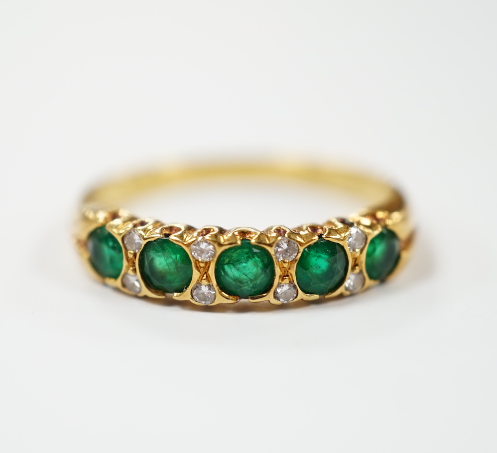 A modern 18ct gold and five stone emerald set half hoop ring, with diamond chip spacers, size K/L, gross weight 3 grams.                                                                                                    