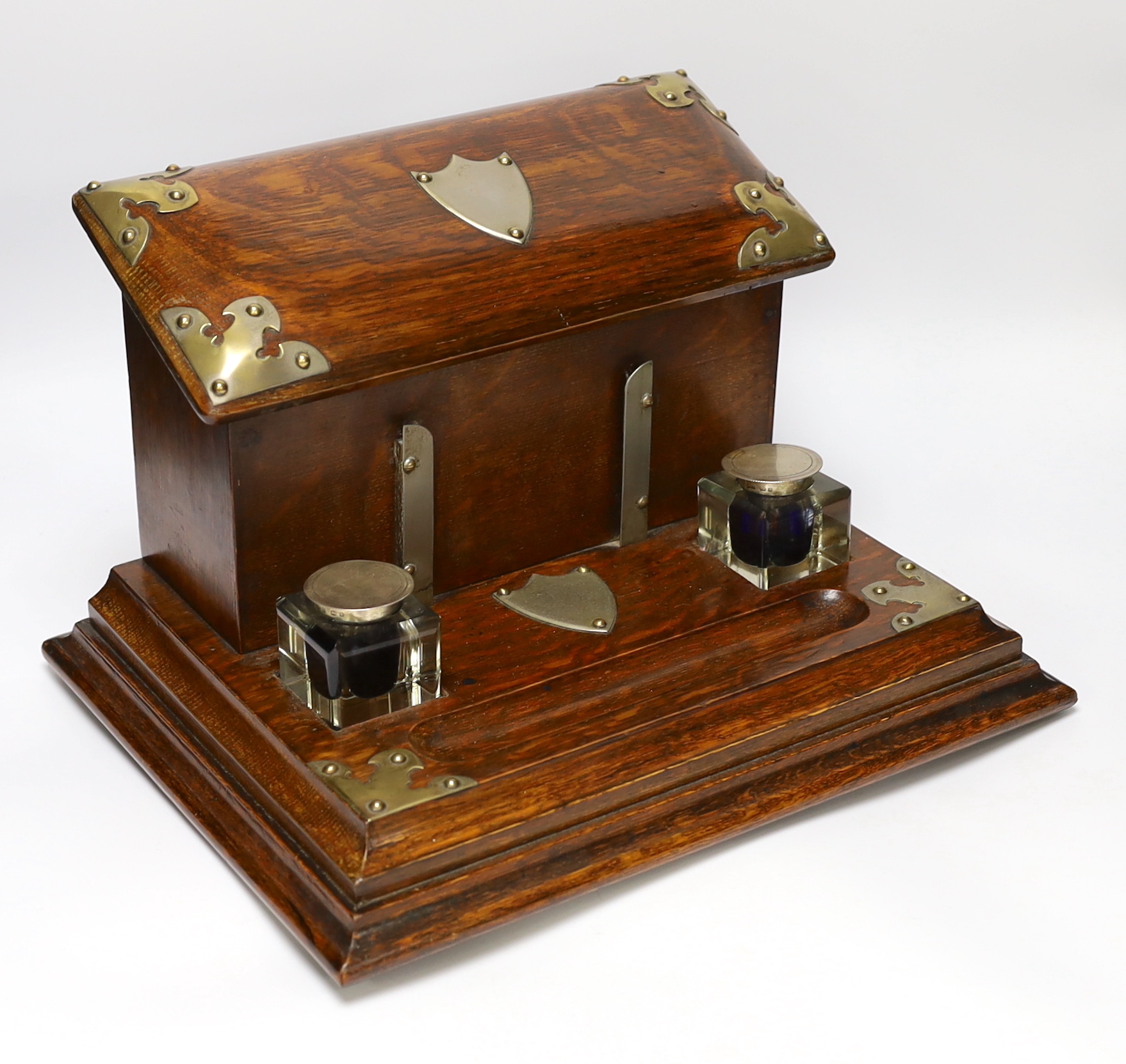 A Victorian brass mounted oak desk stand with two silver mounted glass inkwells, 35cm wide                                                                                                                                  