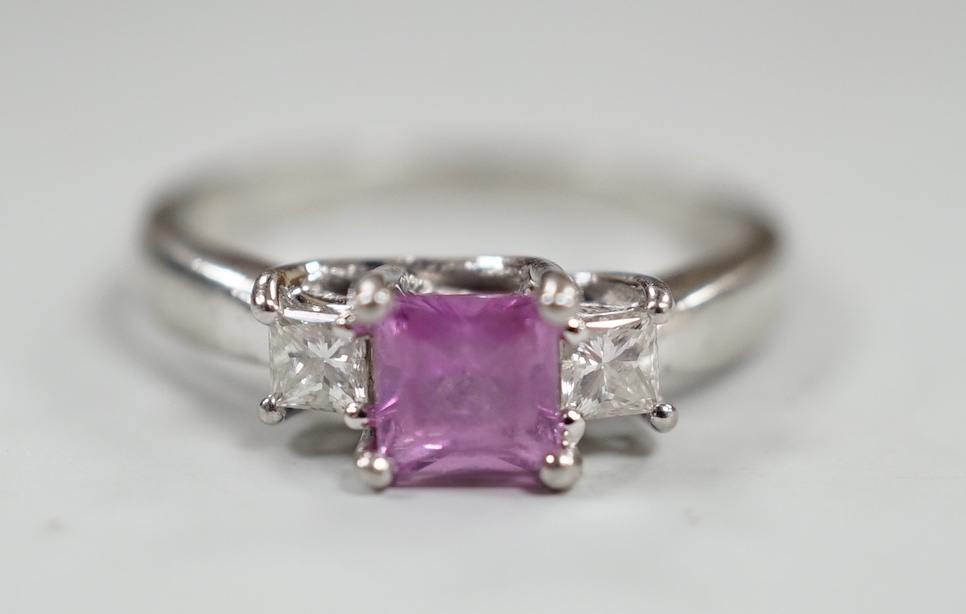 A modern platinum, single stone square cut pink sapphire and two stone diamond set ring, size N/O, gross weight 5.5 grams.                                                                                                  