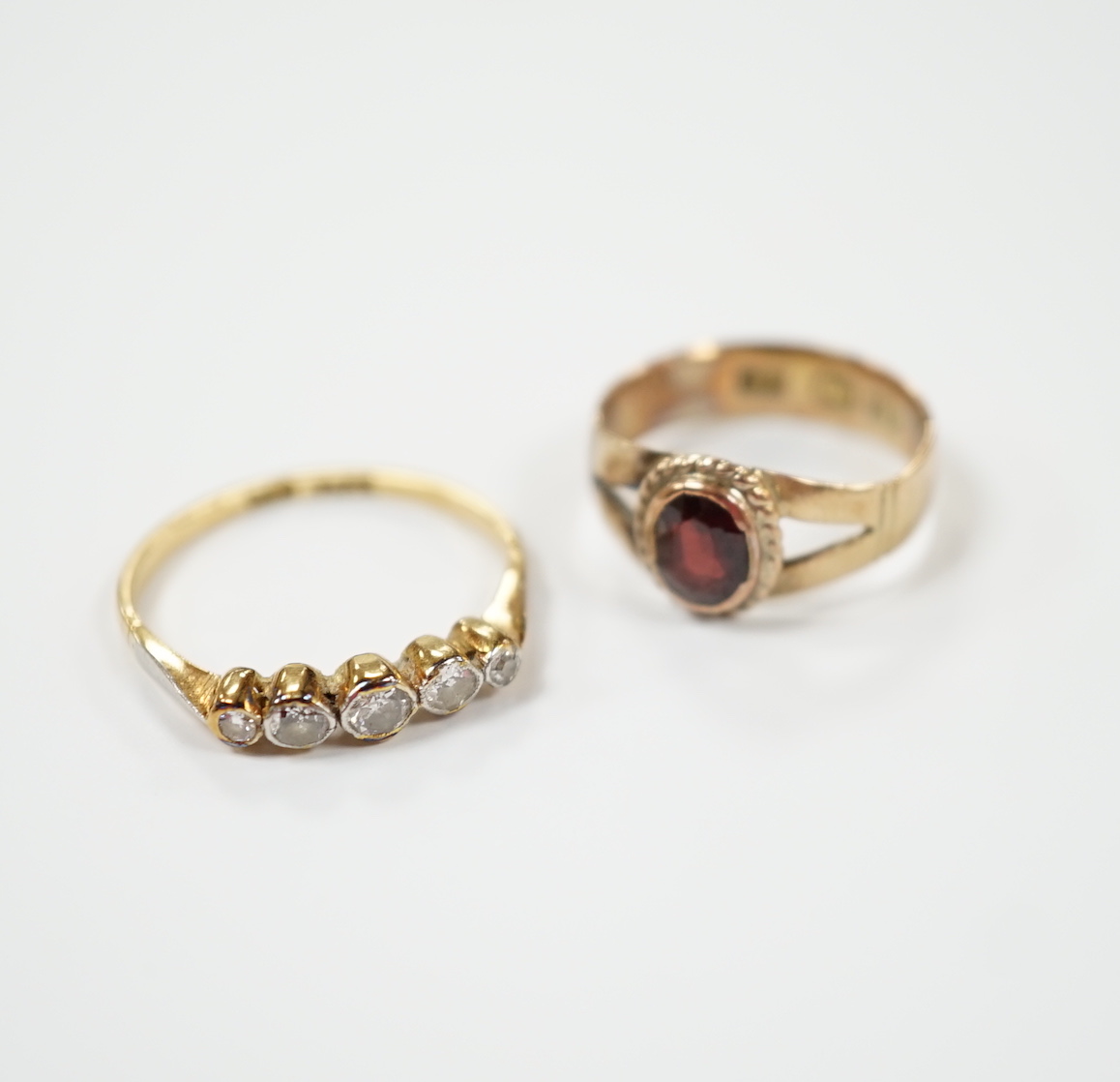 An 18ct, plat and graduated five stone diamond set half hoop ring, size M and a 14k and single stone garnet ring, size H.                                                                                                   