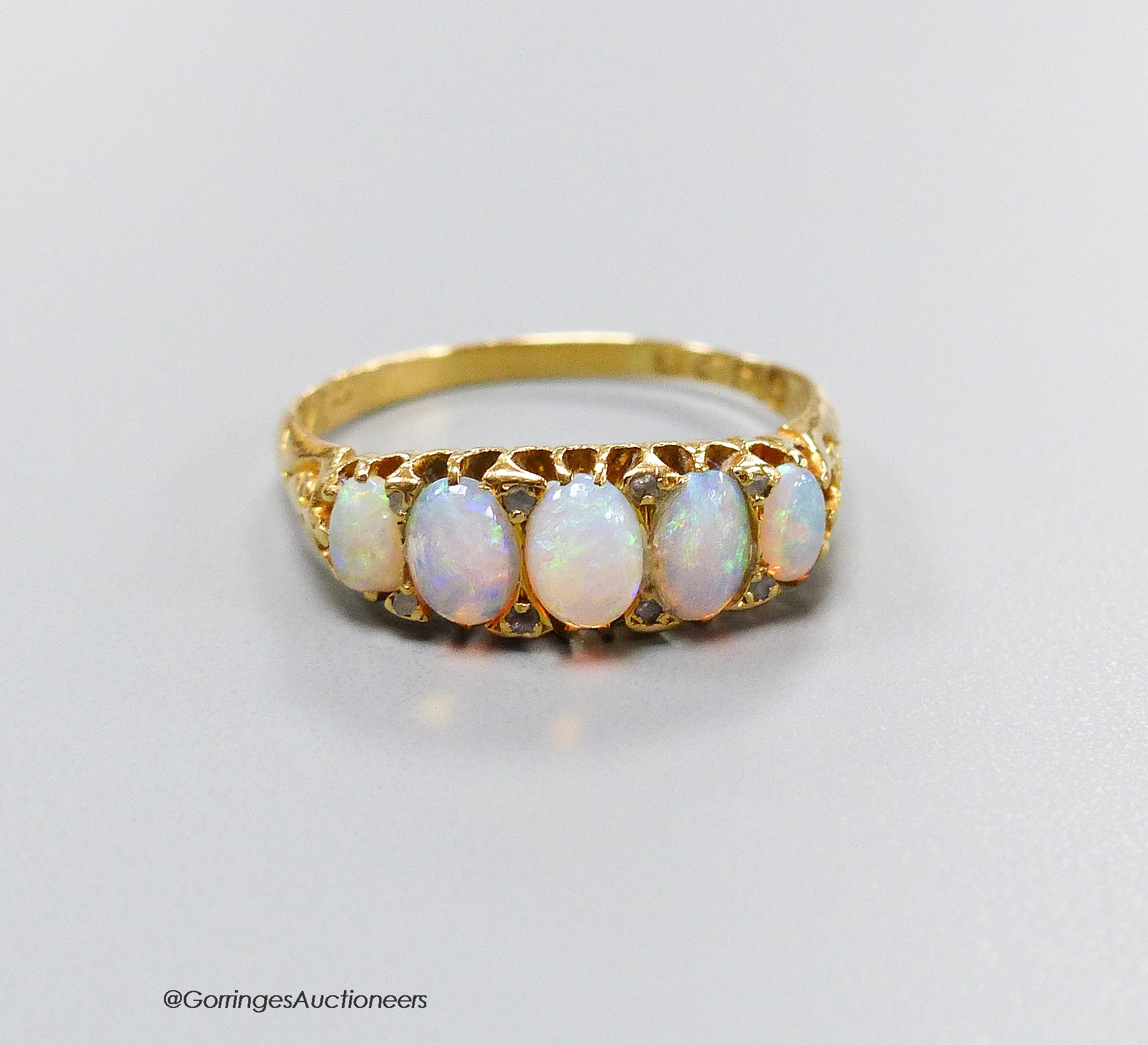 An Edwardian 18ct gold and graduated white opal set half hoop ring, with diamond chip spacers, size Q, gross 3.5 grams                                                                                                      