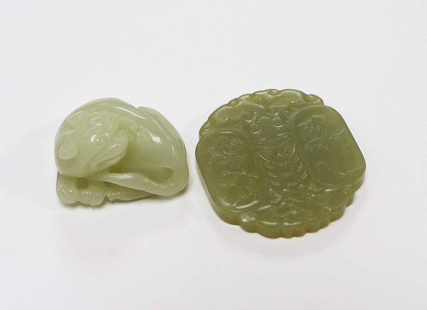 A Chinese carved jade pendant and another carving of a recumbent lion dog, largest 5cm                                                                                                                                      