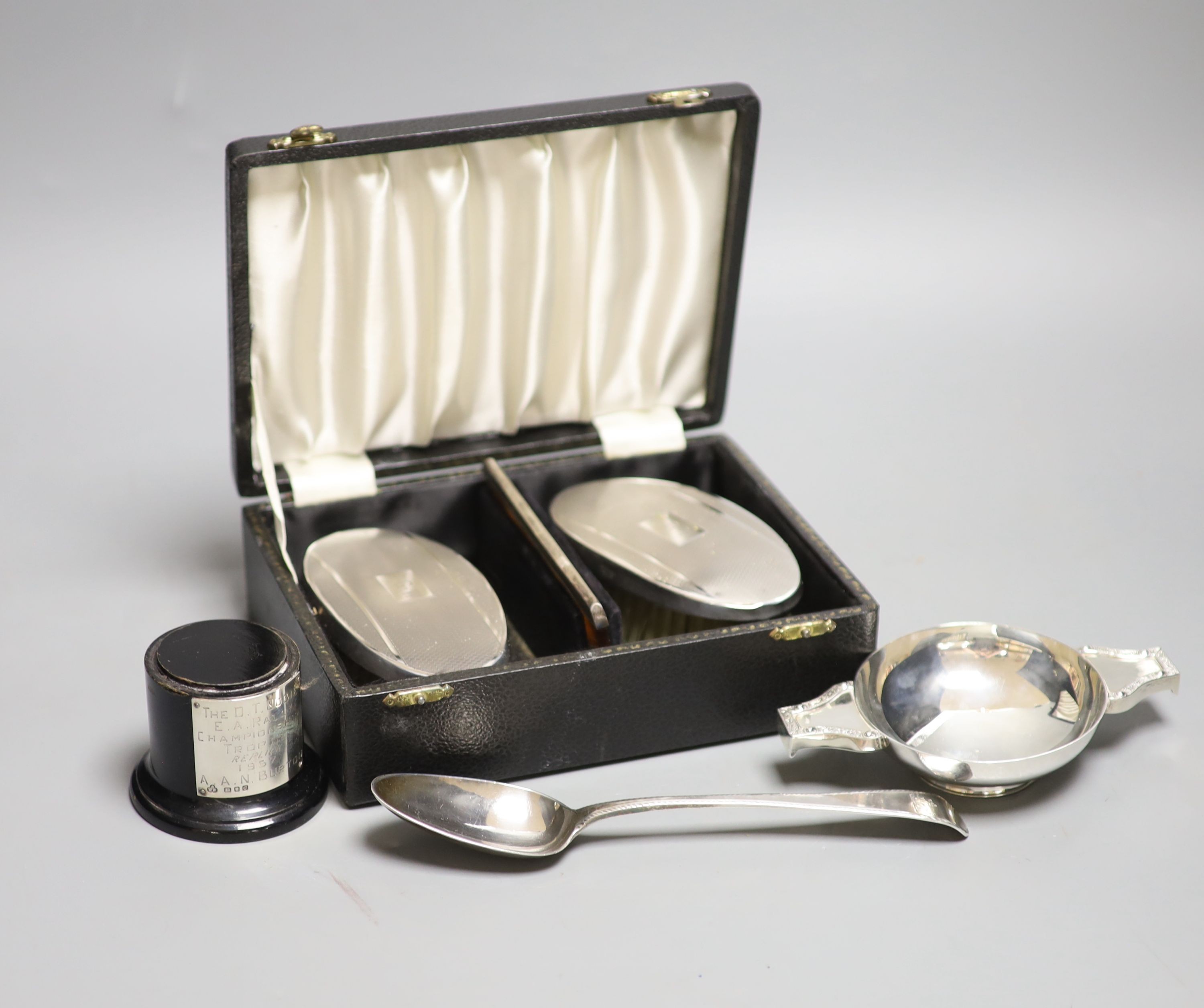 A cased pair of silver clothes brushes, silver quaich-type trophy and a George III silver dessert spoon.                                                                                                                    