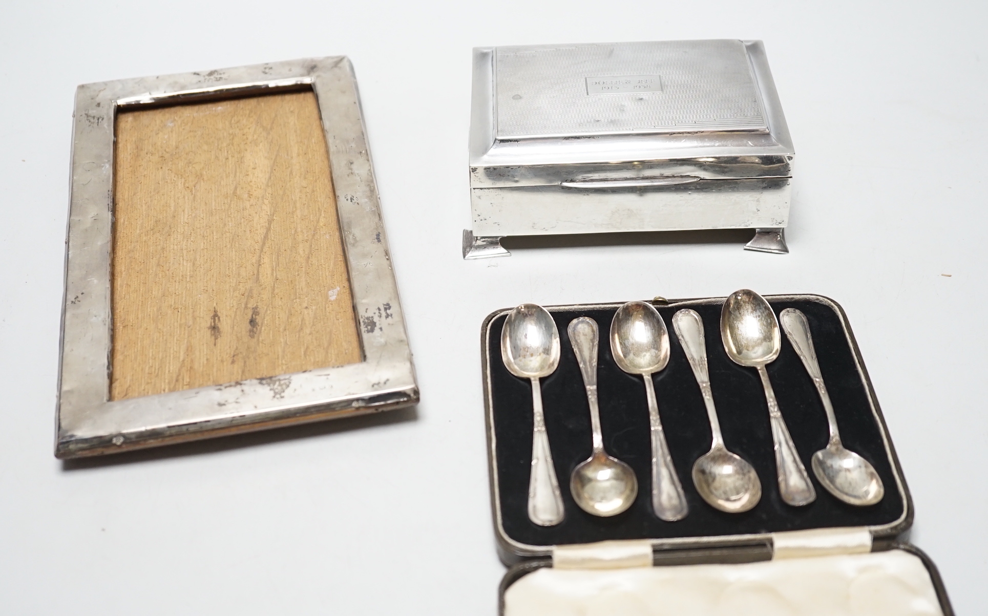 A set of six George VI silver teaspoons, Birmingham, 1939, cased, a silver cigarette box and a silver framed photograph frame.                                                                                              