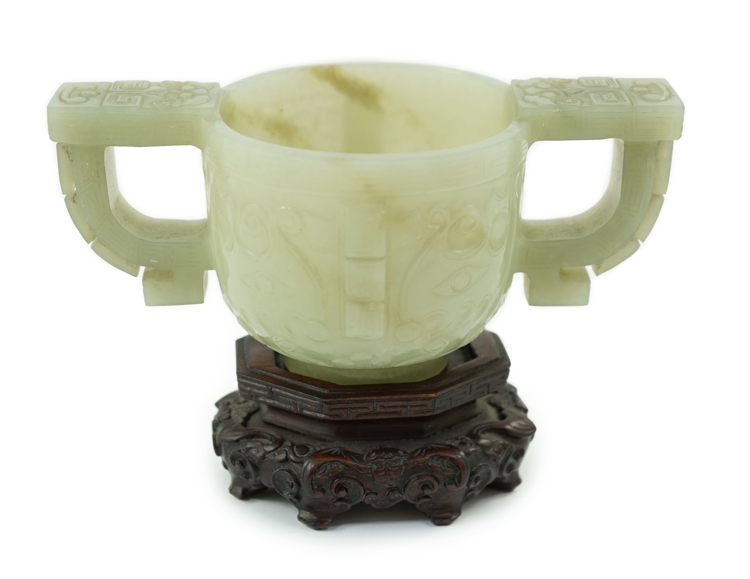 A Chinese archaistic celadon jade two handled cup, 17th century, 12.9cm across 6.1cm high, associated wood stand                                                                                                            