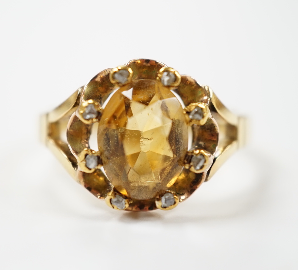 An 18ct and single stone oval cut citrine set dress ring, with eight stone diamond chip set border, size V                                                                                                                  