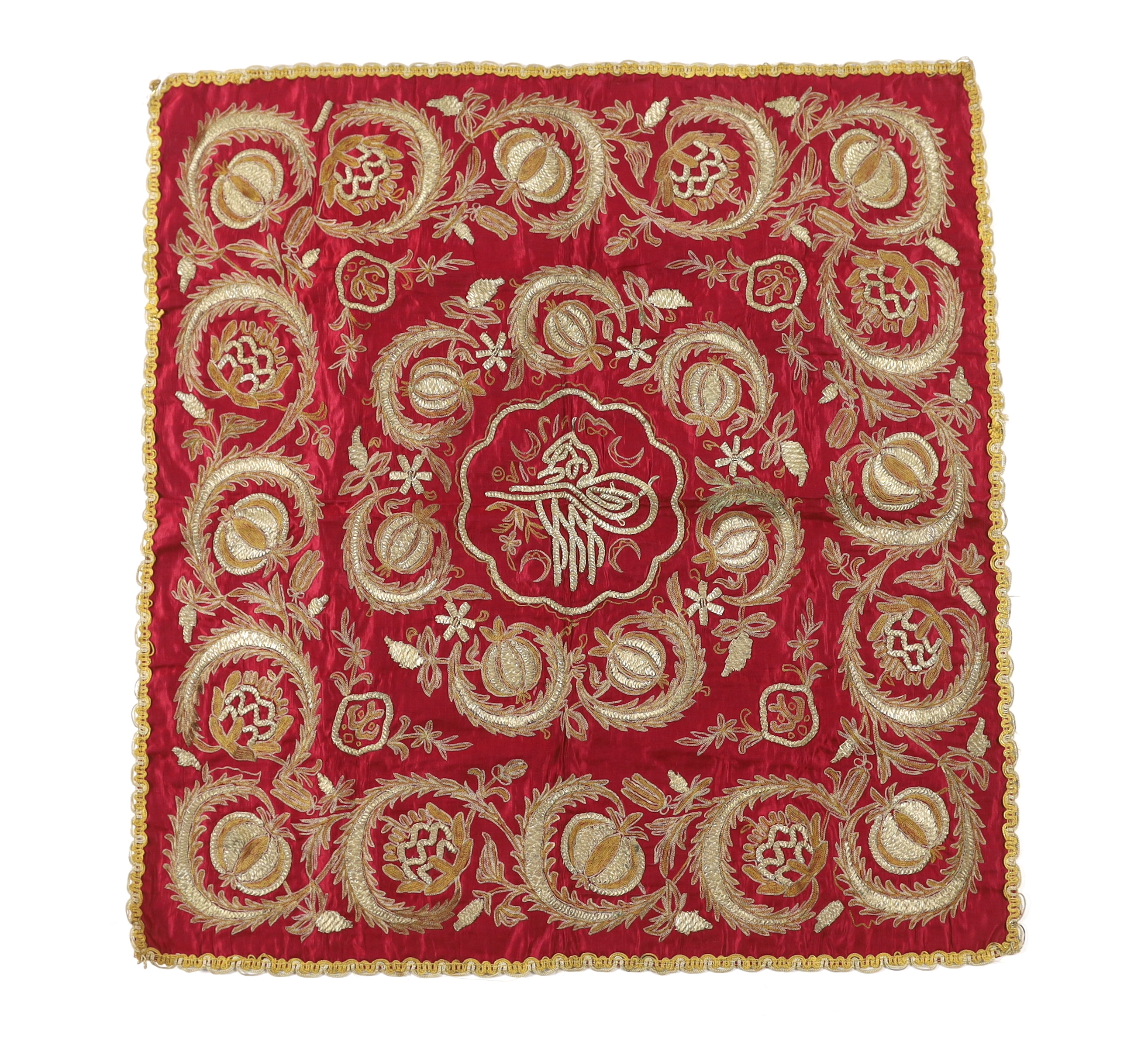 A late 19th century red silk Ottoman metallic thread embroidered cover worked in chain stitch and thick raised embroidery of pomegranate design with a central cartouche, braiding possibly added later, backed with fine li