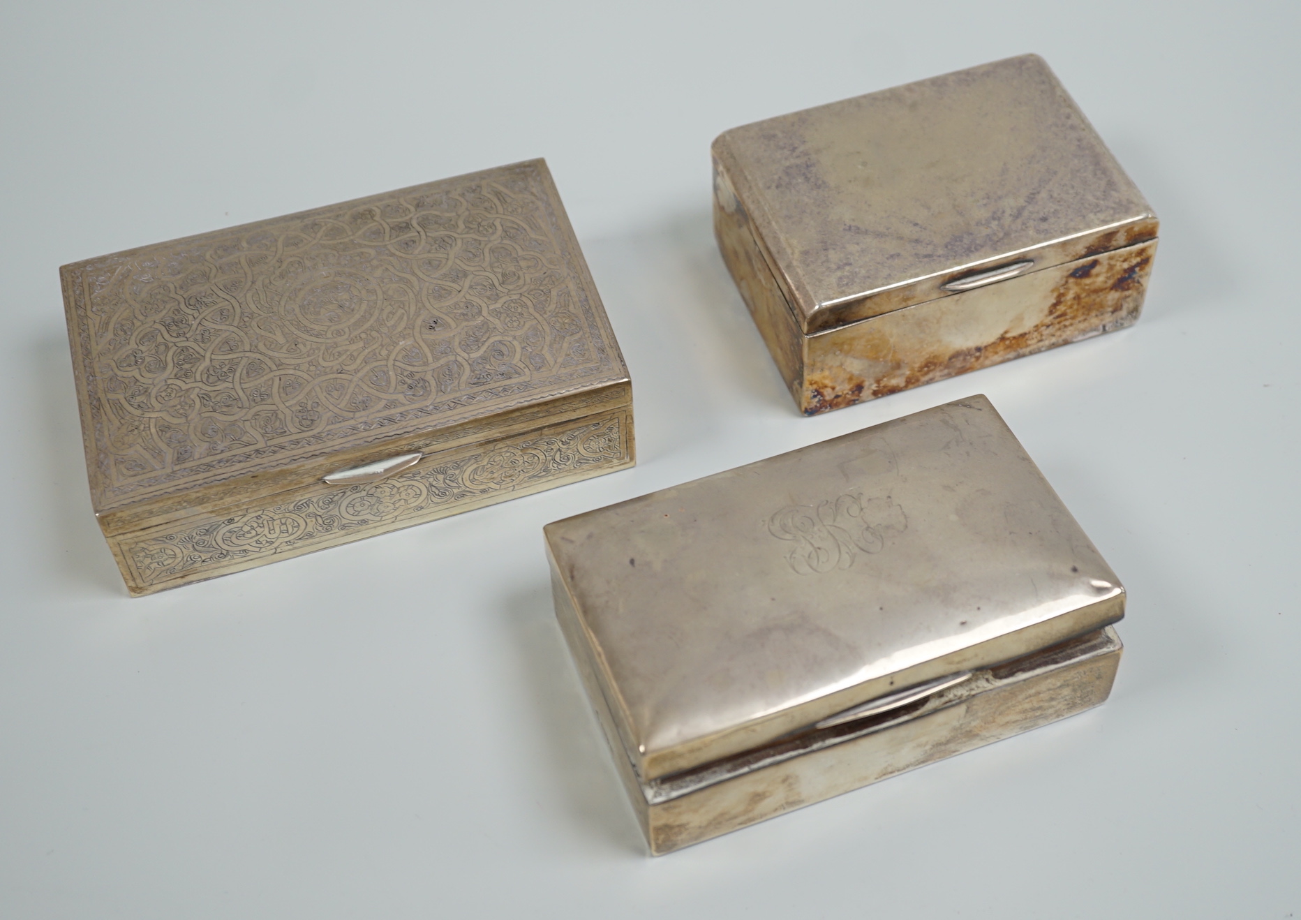 A George V silver mounted cigarette box, 13.9cm, a Persian engraved white metal cigarette box and one other cigarette box.                                                                                                  