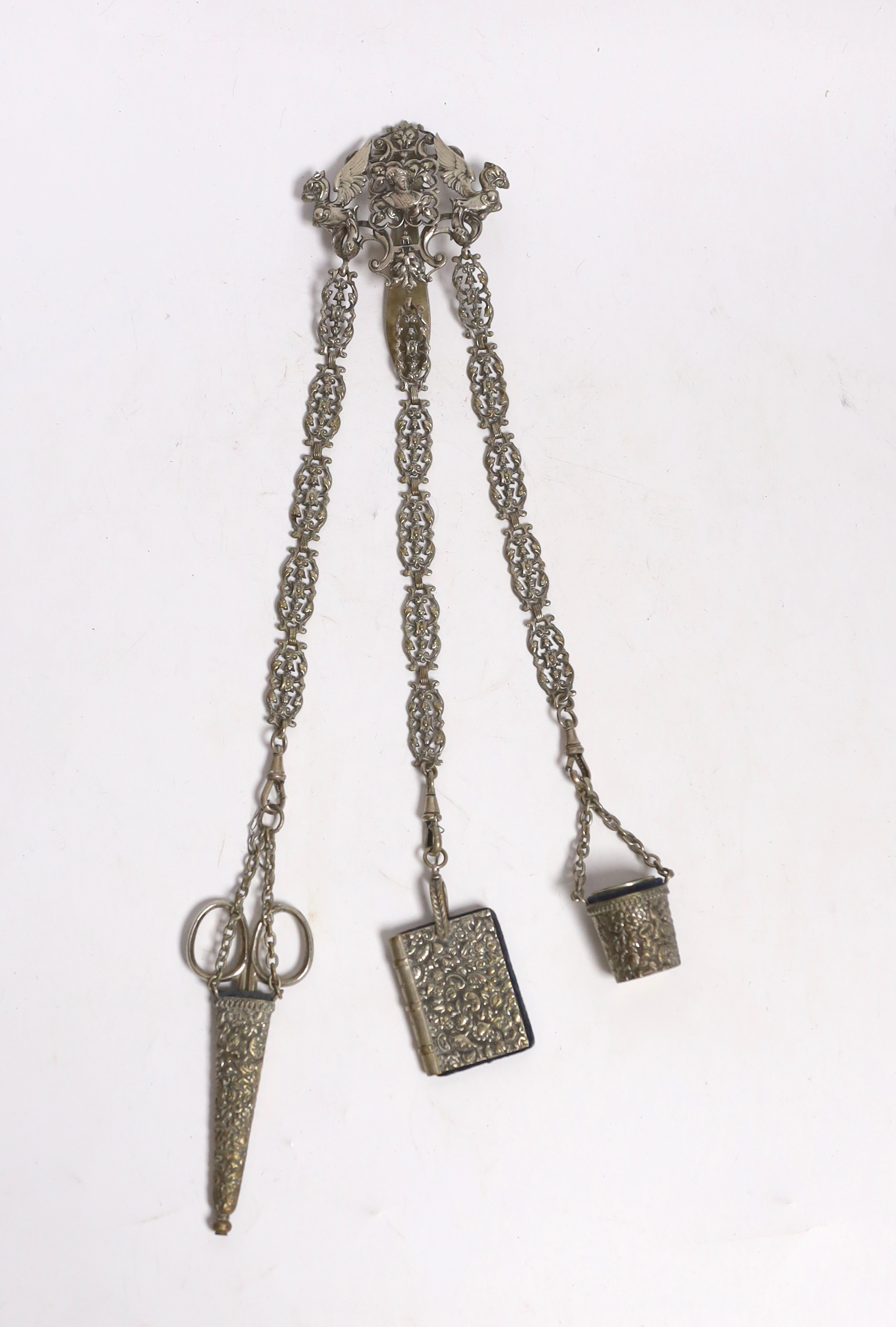 A late 19th century pierced silver plated chatelaine, hung with three accoutrements, to include a cased pair of scissors, pin cushion and thimble holder, overall 29.5cm.                                                   