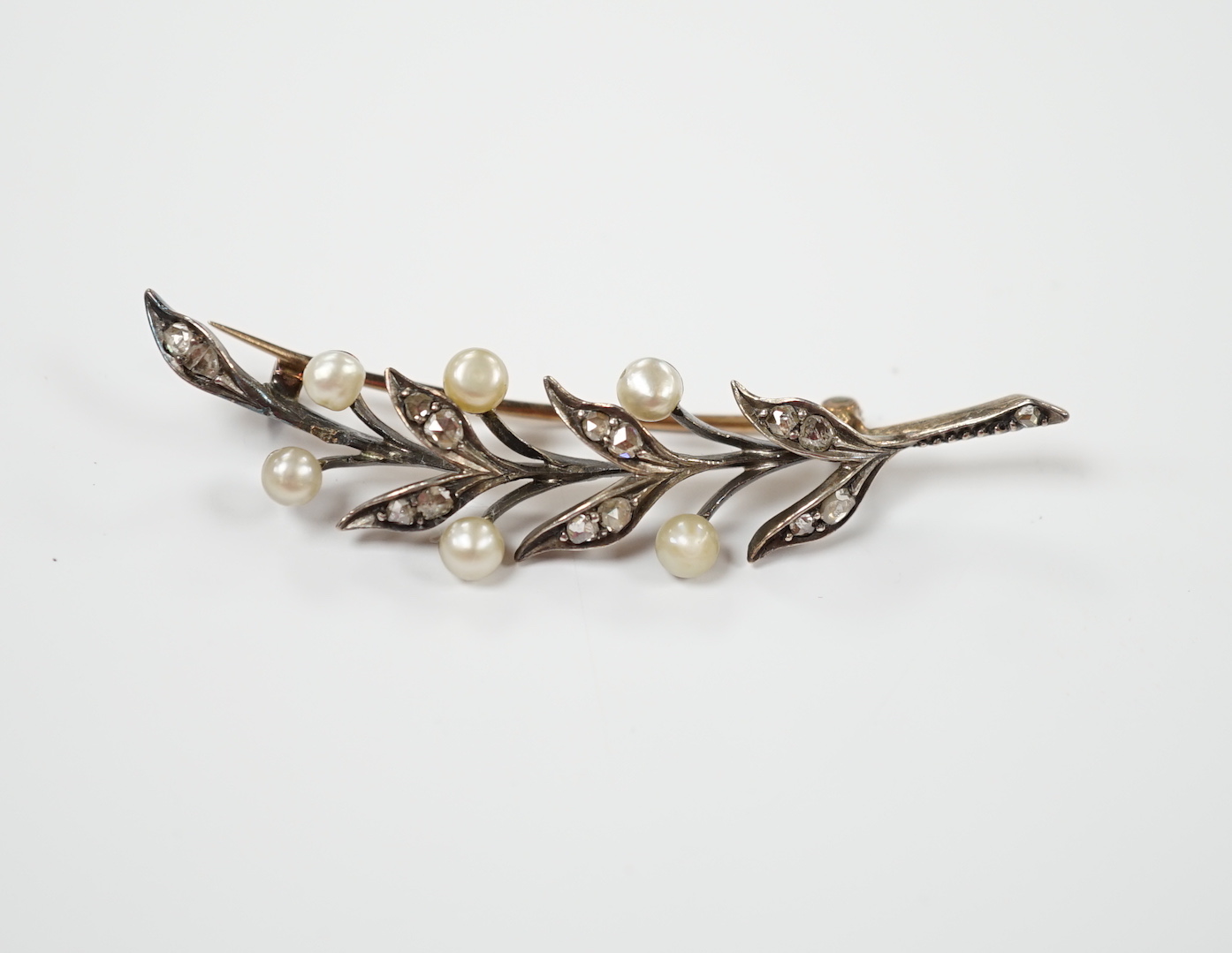 An early 20th century yellow metal, cultured pearl and rose cut diamond set foliate spray brooch, 58mm, gross weight 5.8 grams.                                                                                             
