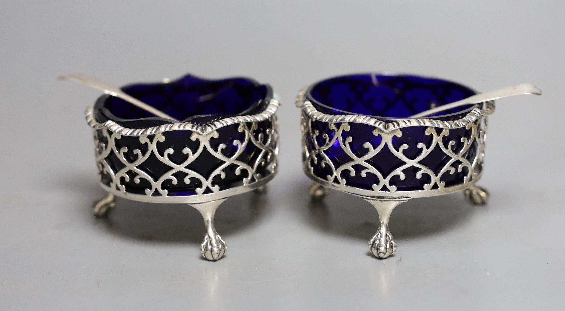 A pair of George III pierced silver circular salts, London, 1764, 79mm, with two associated spoons.                                                                                                                         