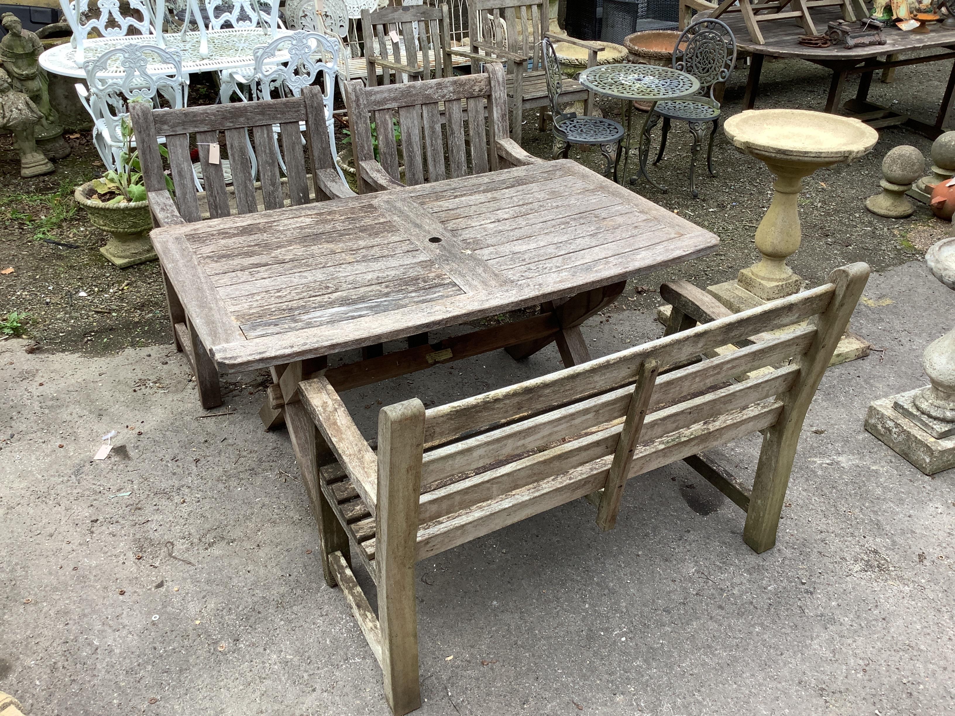 A rectangular weathered teak garden table, width 152cm, depth 86cm, height 74cm, together with a teak garden bench and two armchairs                                                                                        