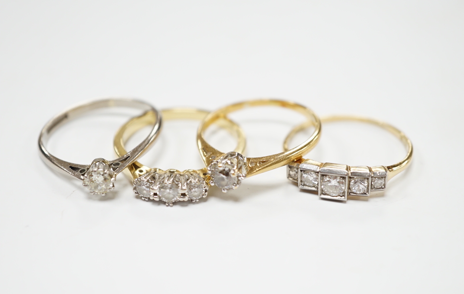 Four assorted 18ct and diamond set rings including a graduated five stone, three stone and two solitaires, gross weight 10.3 grams.                                                                                         
