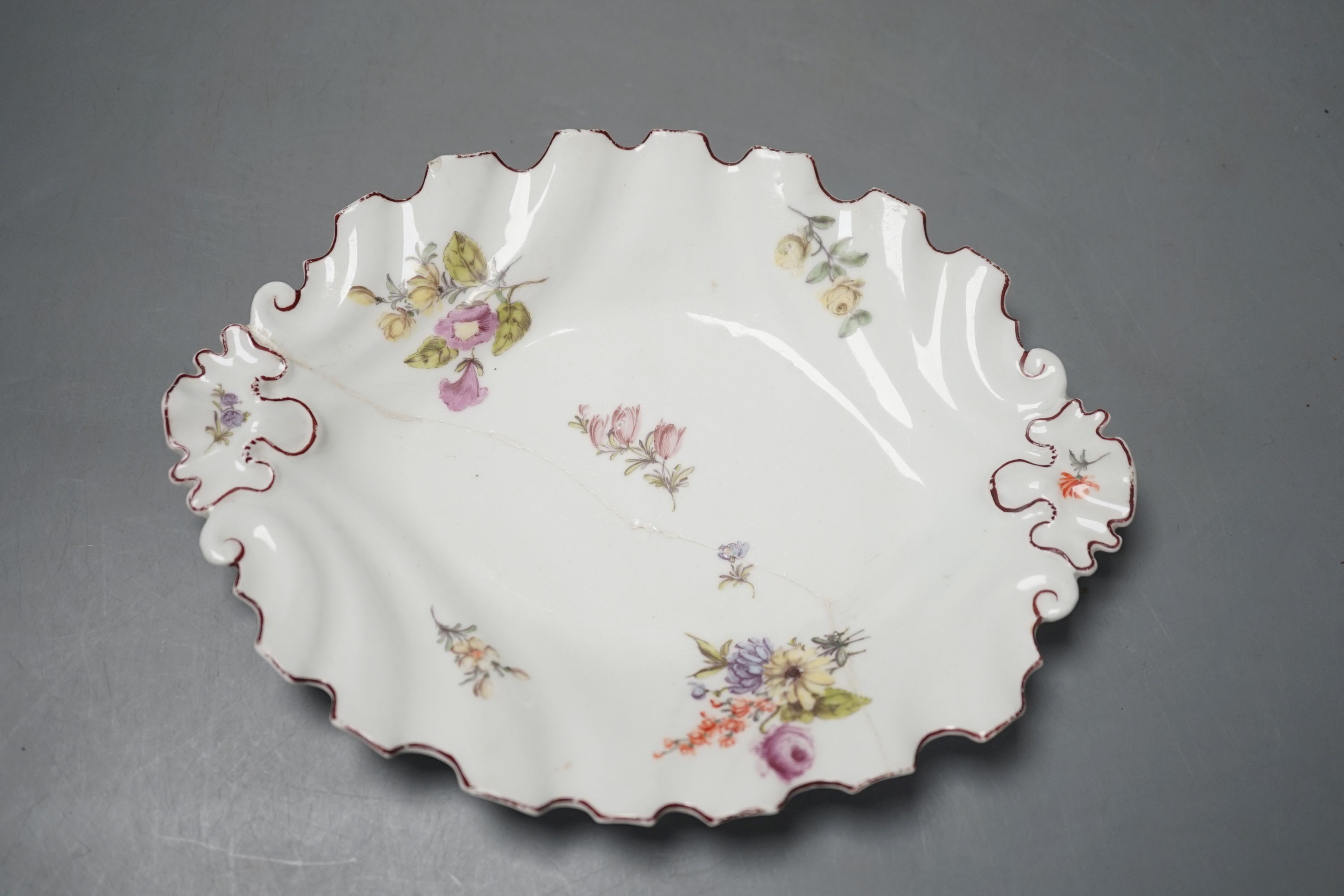 A Chelsea silver shaped dish painted with scattered English flowers under a brown line rim, red anchor and stilt marks c. 1755, 21 cms wide.                                                                                