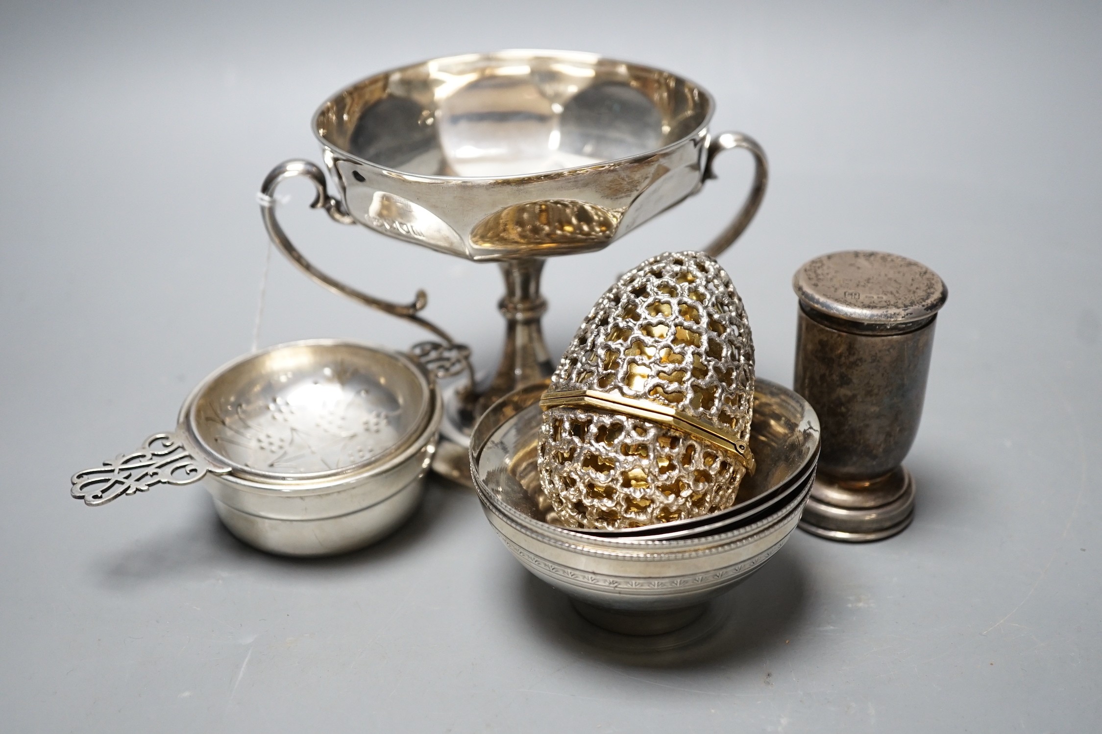 Small silver including Edwardian two handled pedestal bowl, Goldsmiths & Silversmiths Co Ltd, London, 1907, 97mm, a later silver tea strainer on stand, four Egyptian white metal finger bowls, a George VI communion set, L