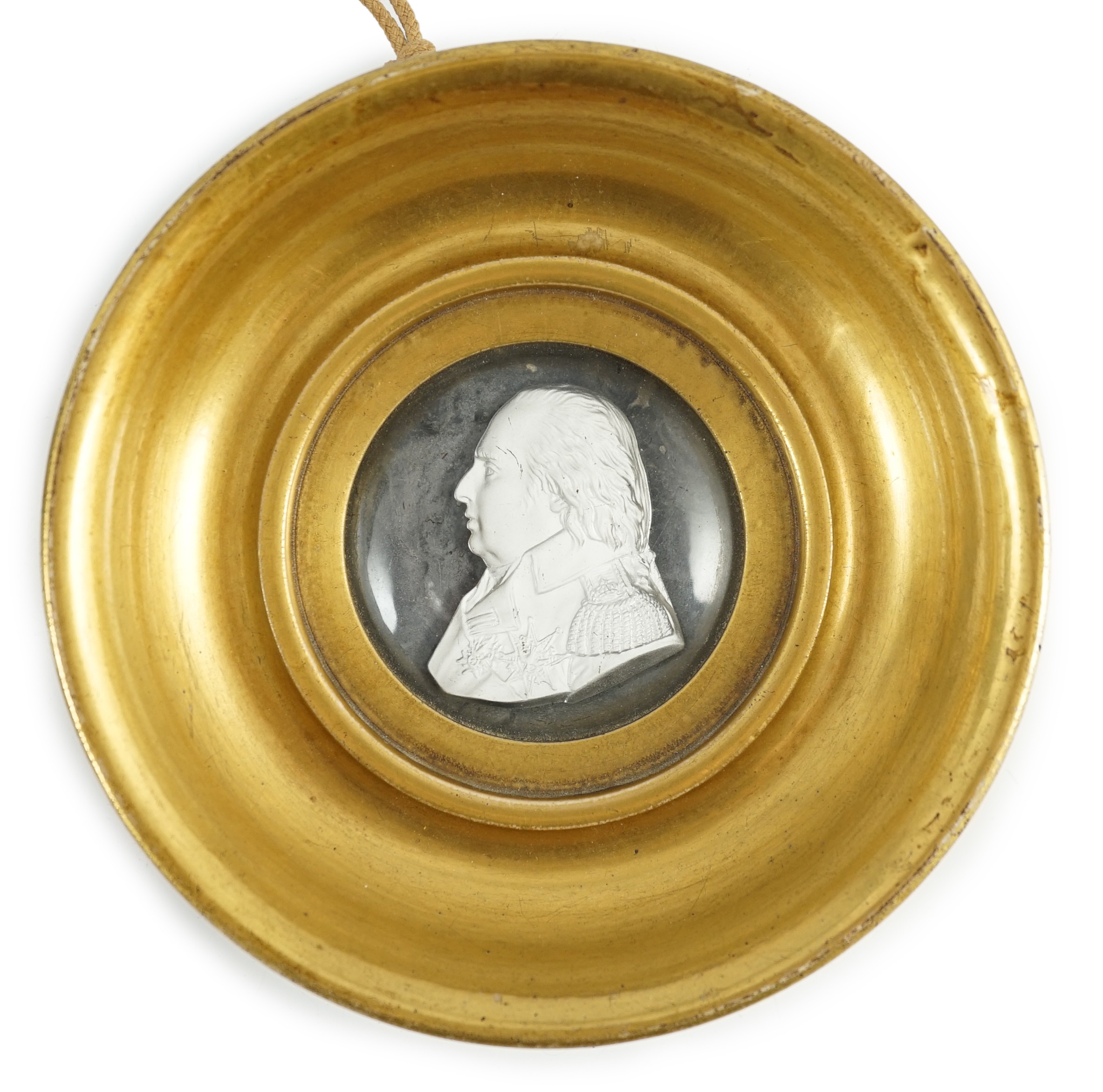 A Louis XVIII glass sulphide portrait plaque, in a gilded porcelain frame, c.1820, 14.5cm diameter                                                                                                                          