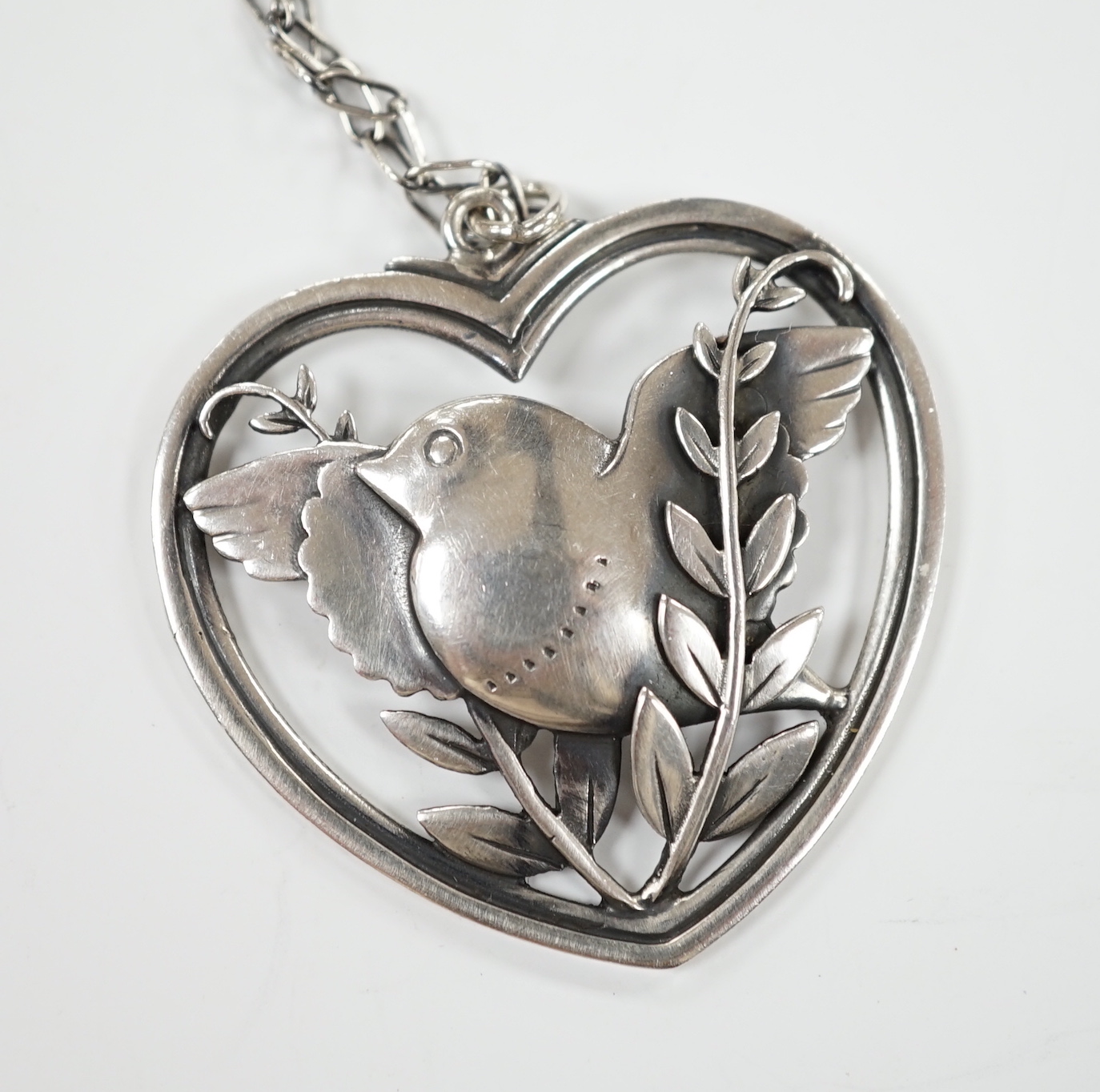 A Georg Jensen sterling heart shaped 'Robin with frond' pendant, on chain, design no. 97, width 39mm.                                                                                                                       