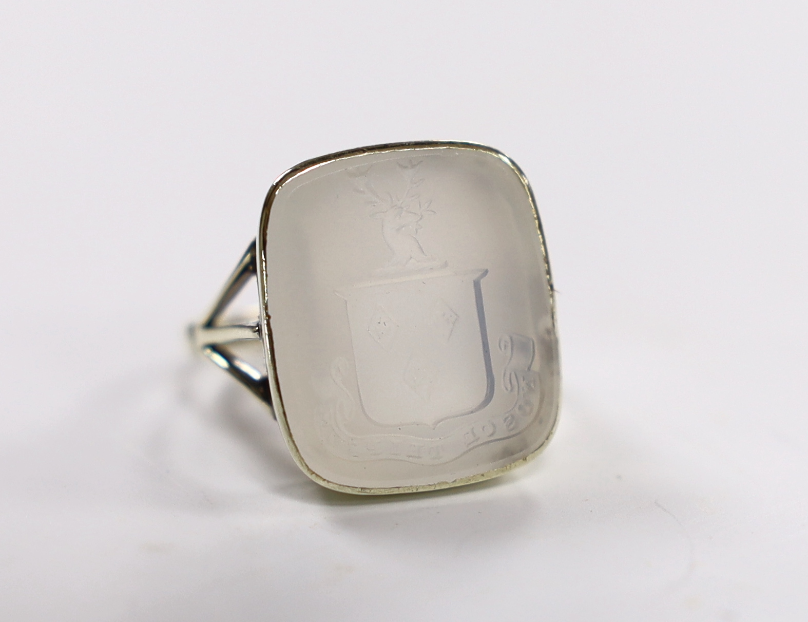 An early 20th century 9ct and white chalcedony set intaglio ring, the matrix carved with family crest and motto, size K, gross weight 5.5 grams.                                                                            