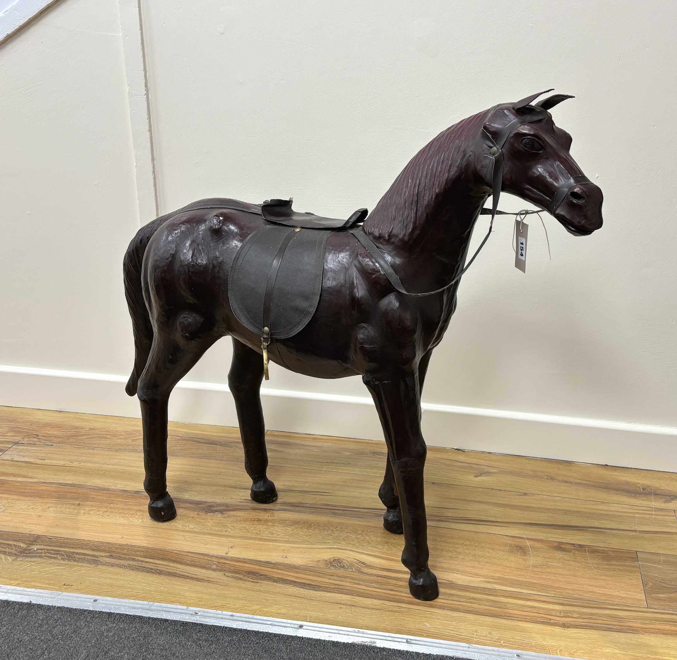 A burgundy leather covered model of a horse with faux leather tack, height 76cm                                                                                                                                             