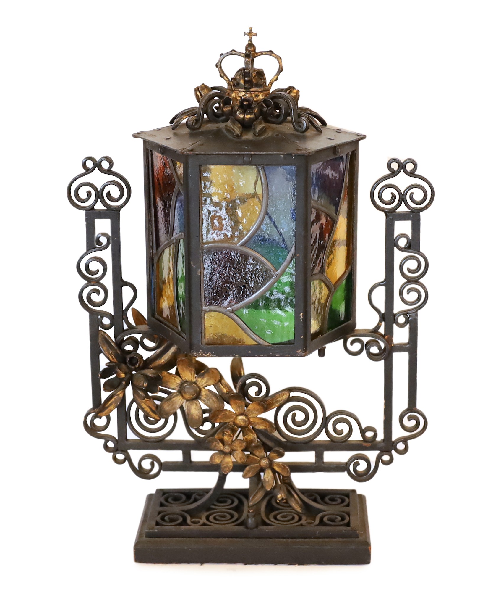 An early 20th century English wrought iron and stained-glass hexagonal lantern style table lamp with crown finial and parcel built black painted finish, height 50cm. width 32cm                                            